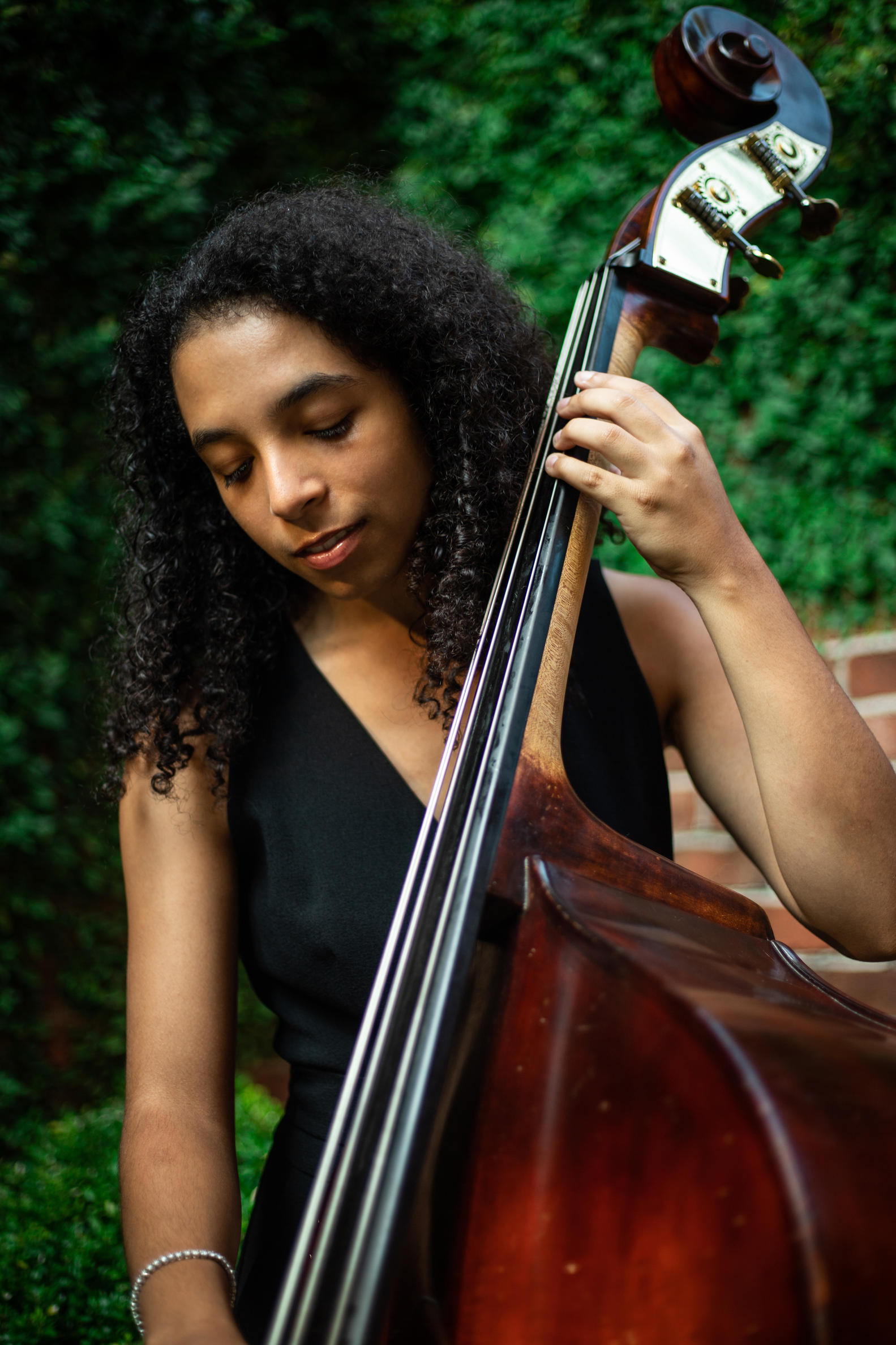Standing image of Devon Gates playing a bass in a black dress. 