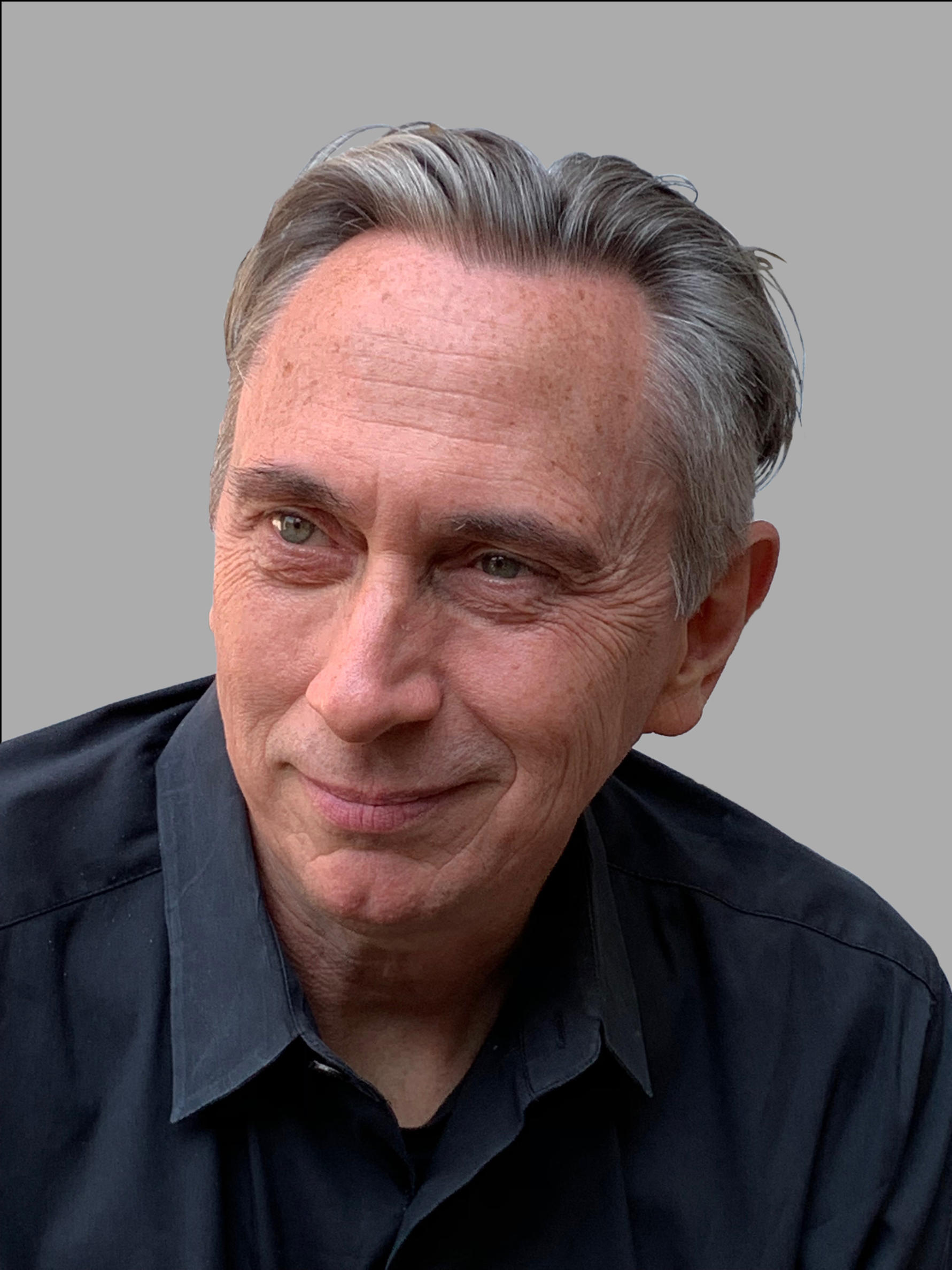 Head shot of a man with grey hair looking to the right with a grey shirt