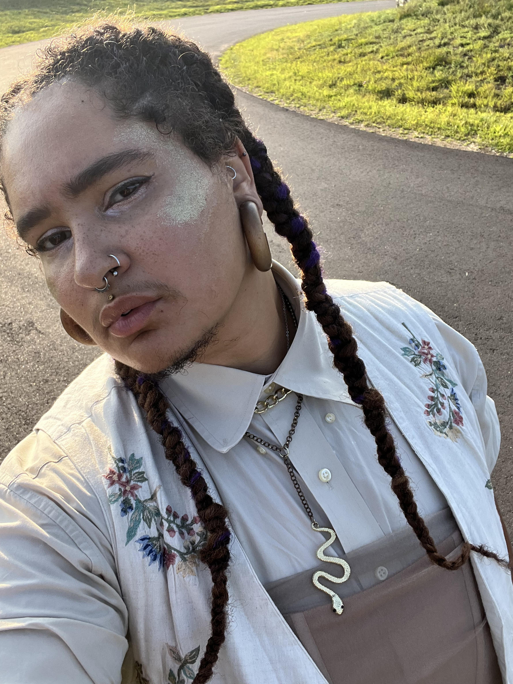 Zenaida Peterson with long braids, white flowered top, tan overall bib with a silver snake necklace