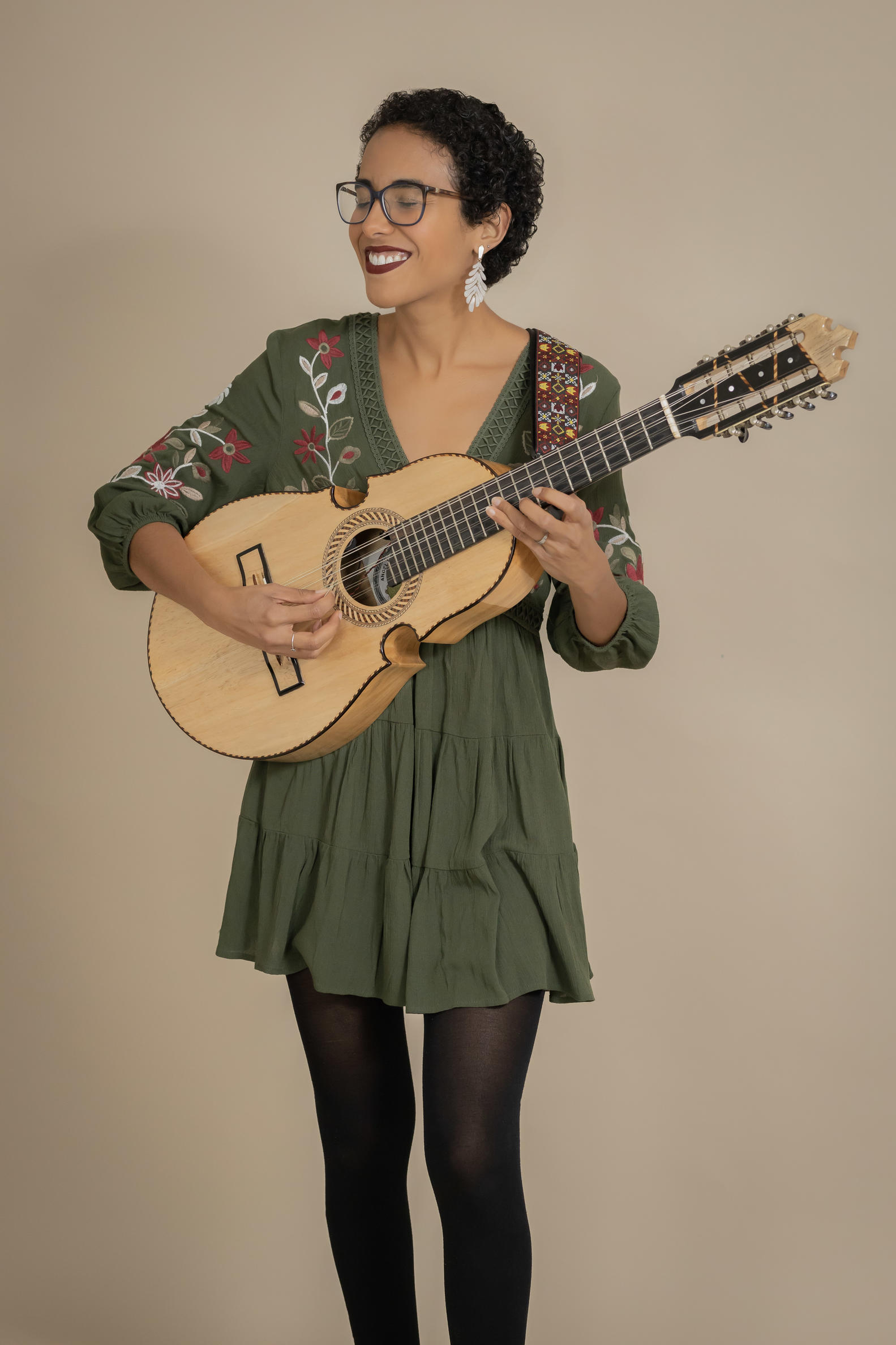 Woman in a green dress, standing, playing the guitar 