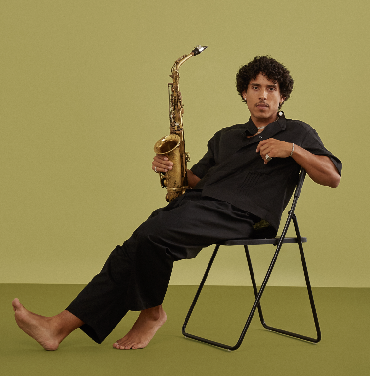 Man lounging in a metal chair holding a saxophone 