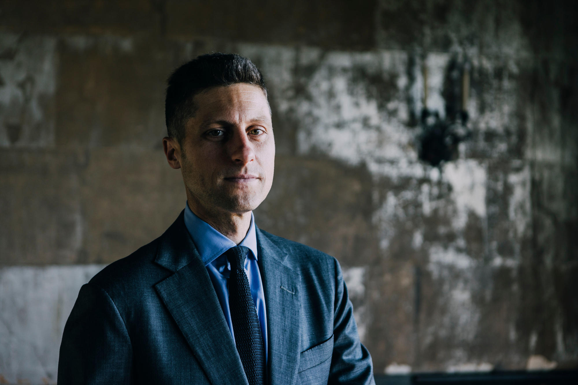 Man with short hair in a blue suit with tie. 