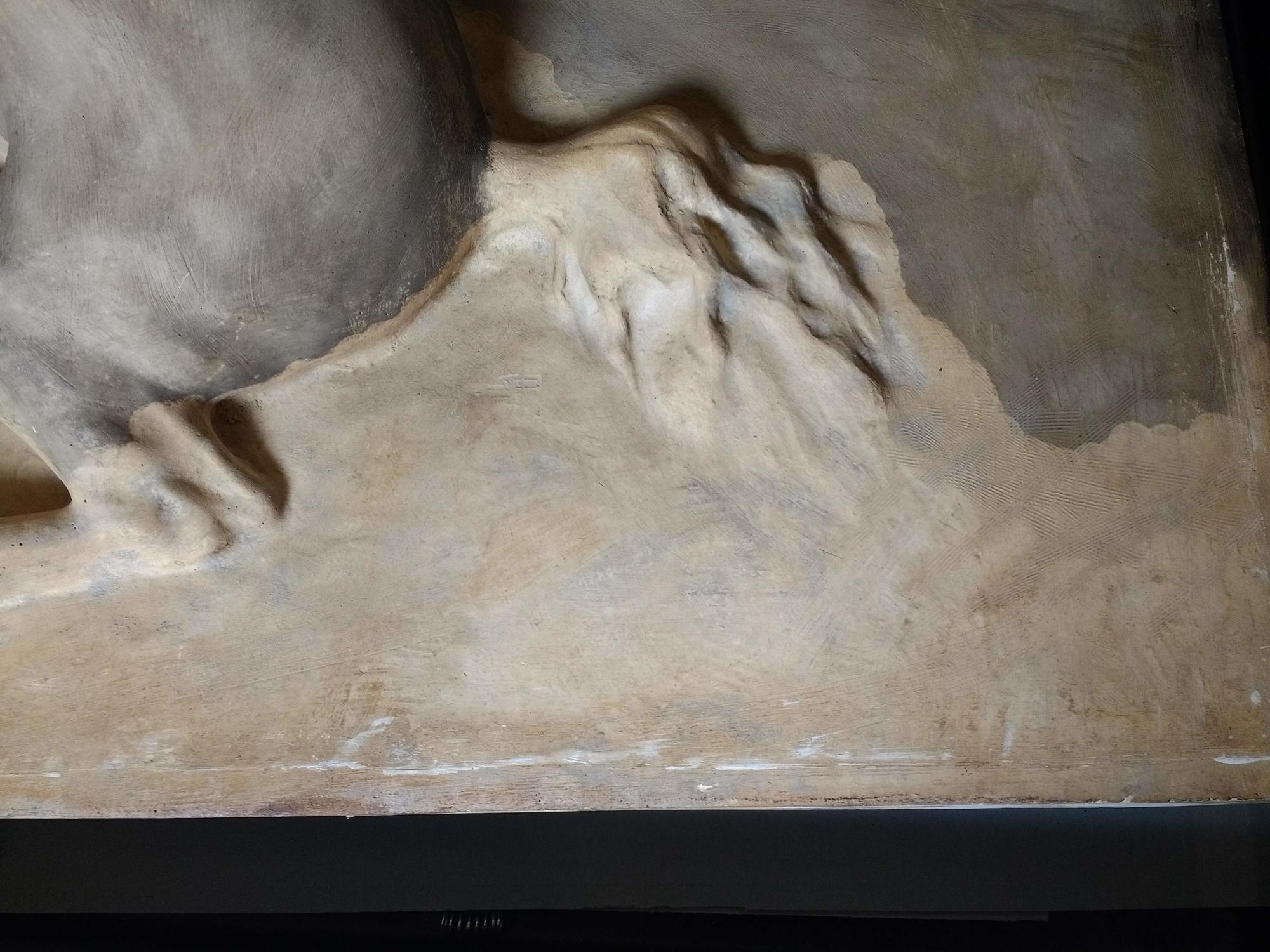 A zoomed in portion of a plaster cast cleaned using a laser showing scattered spots darkened to light gray.