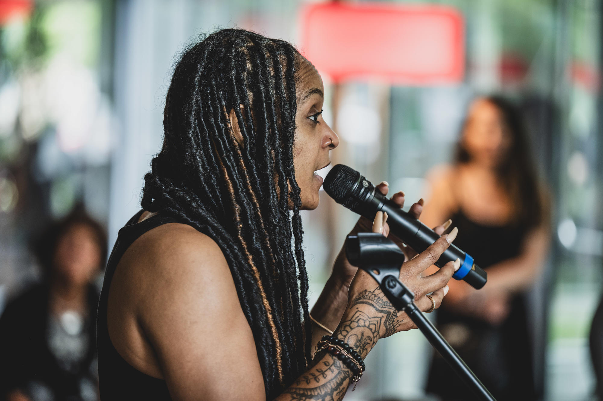Woman with long dread locks speaking into a microphone 