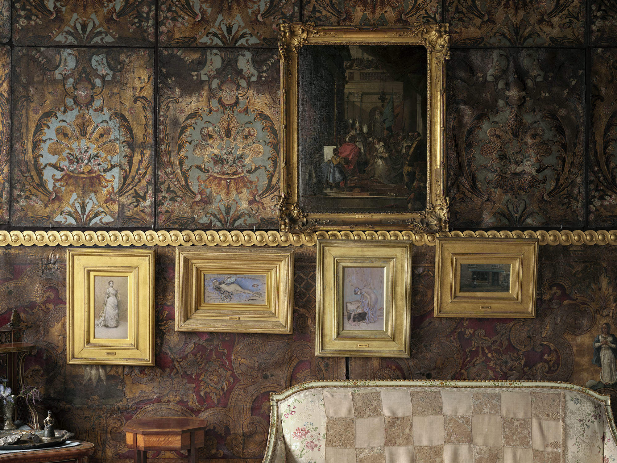 Four artworks in gold frames hung on a wall.