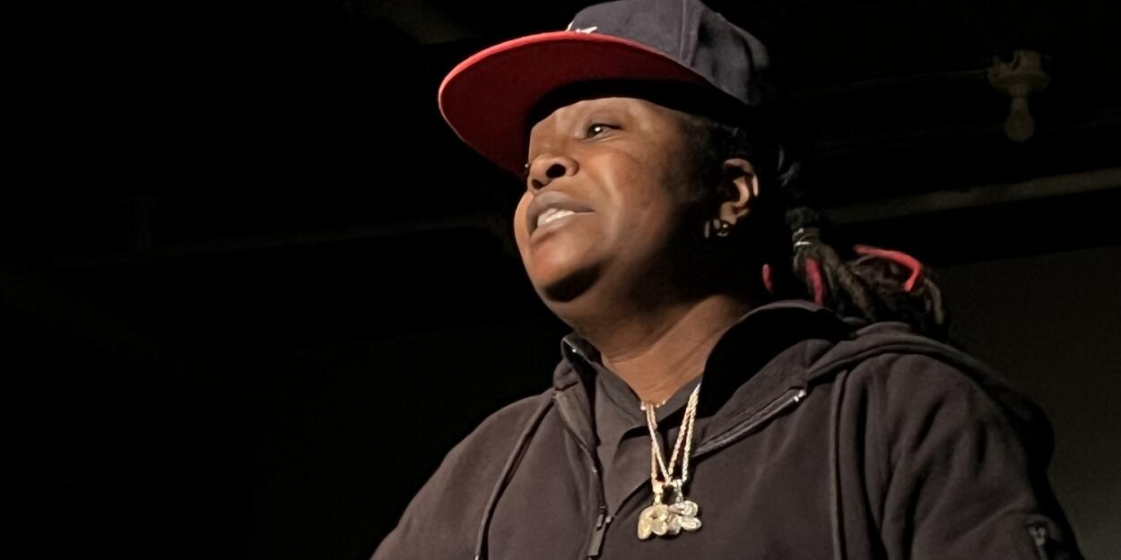 African American woman with a baseball cap and dark grey sweatshirt looking off to the side