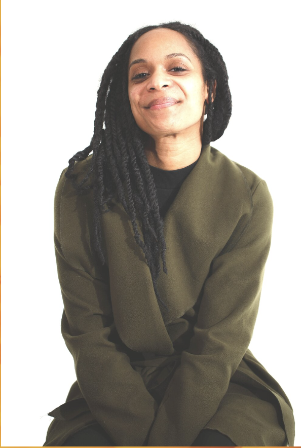 Young African American Woman with long braides wear a black top under a green sweater smiling at the camera 