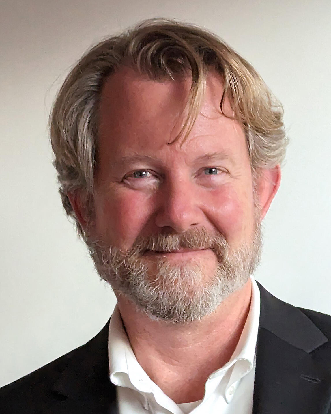 Headshot of a man with blond hair and a grey beard and mustache