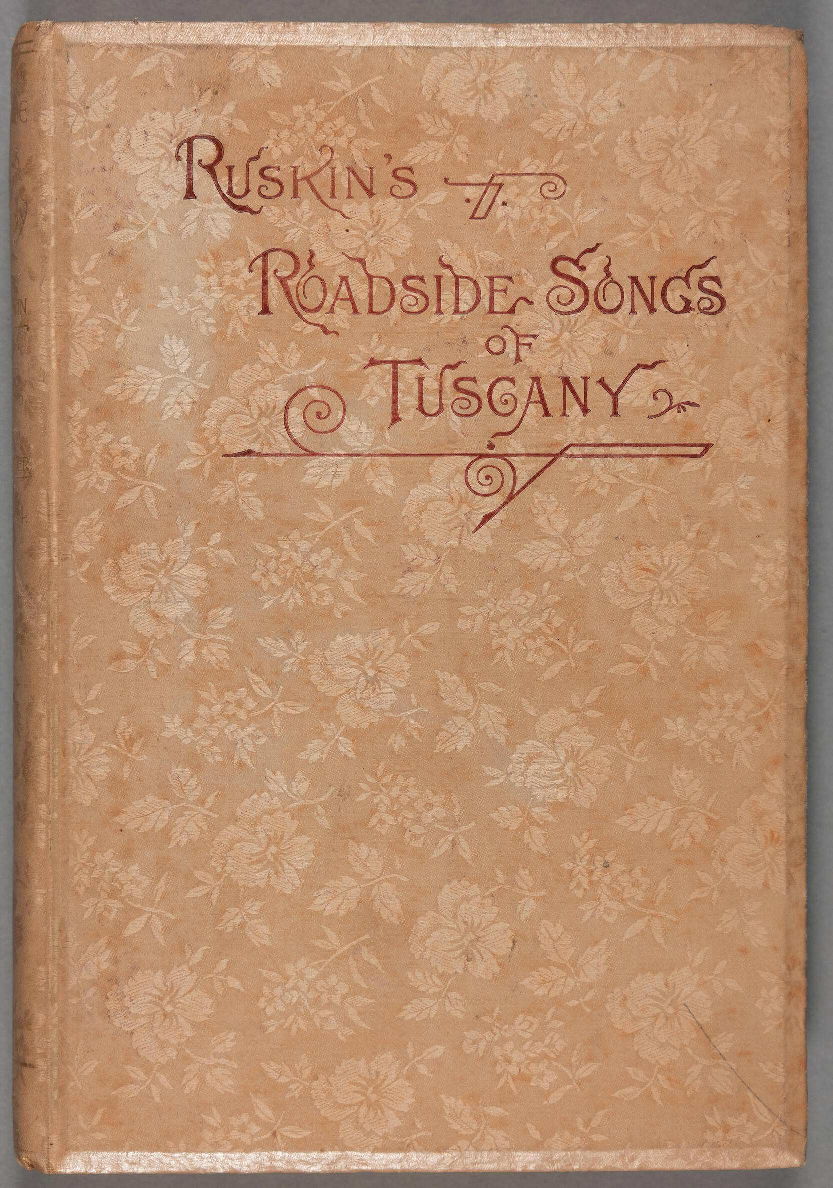 A beige book cover printed with flowers and title John Ruskin’s Roadside Songs of Tuscany.