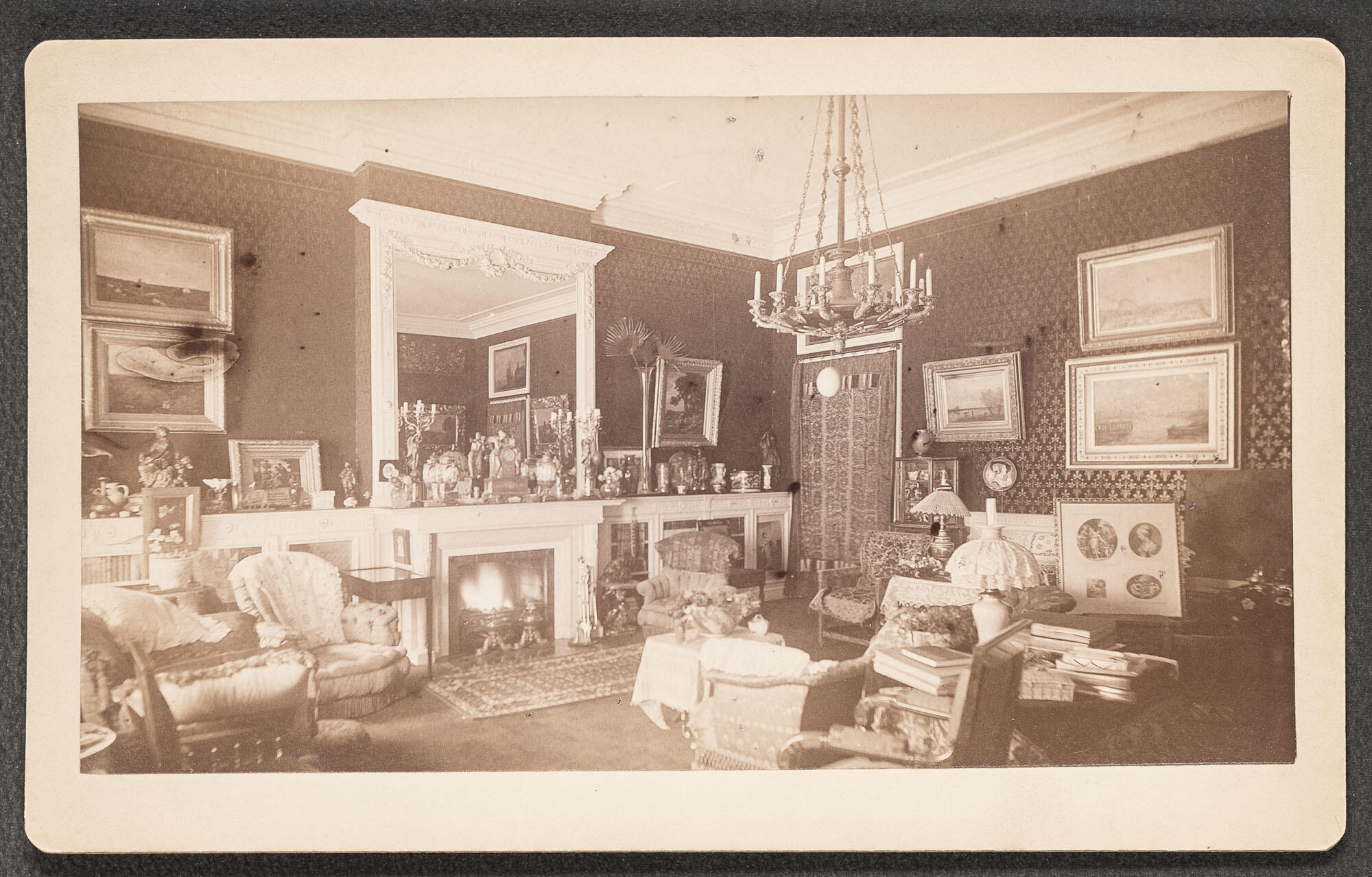 Black and white photograph of Gardner’s densely furnished and decorated drawing room at her Beacon Street residence. An ostrich egg hangs prominently from the central chandelier and the emu egg hangs from a candelabra on the mantle.