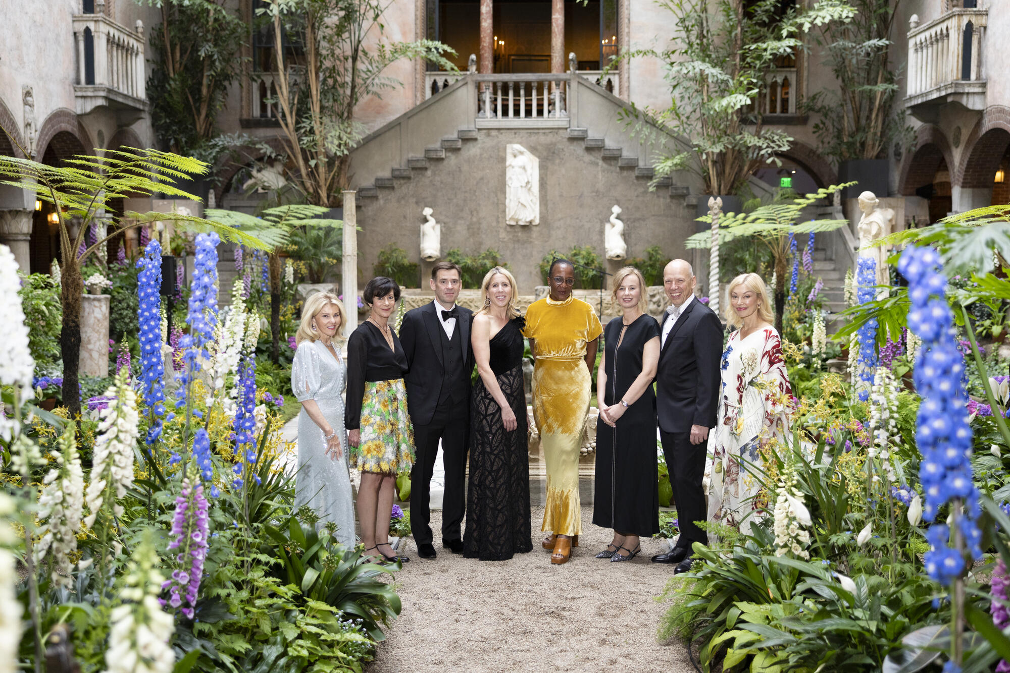 Eight elegantly attired adults in tuxedos and gowns in the middle of the Courtyard.  