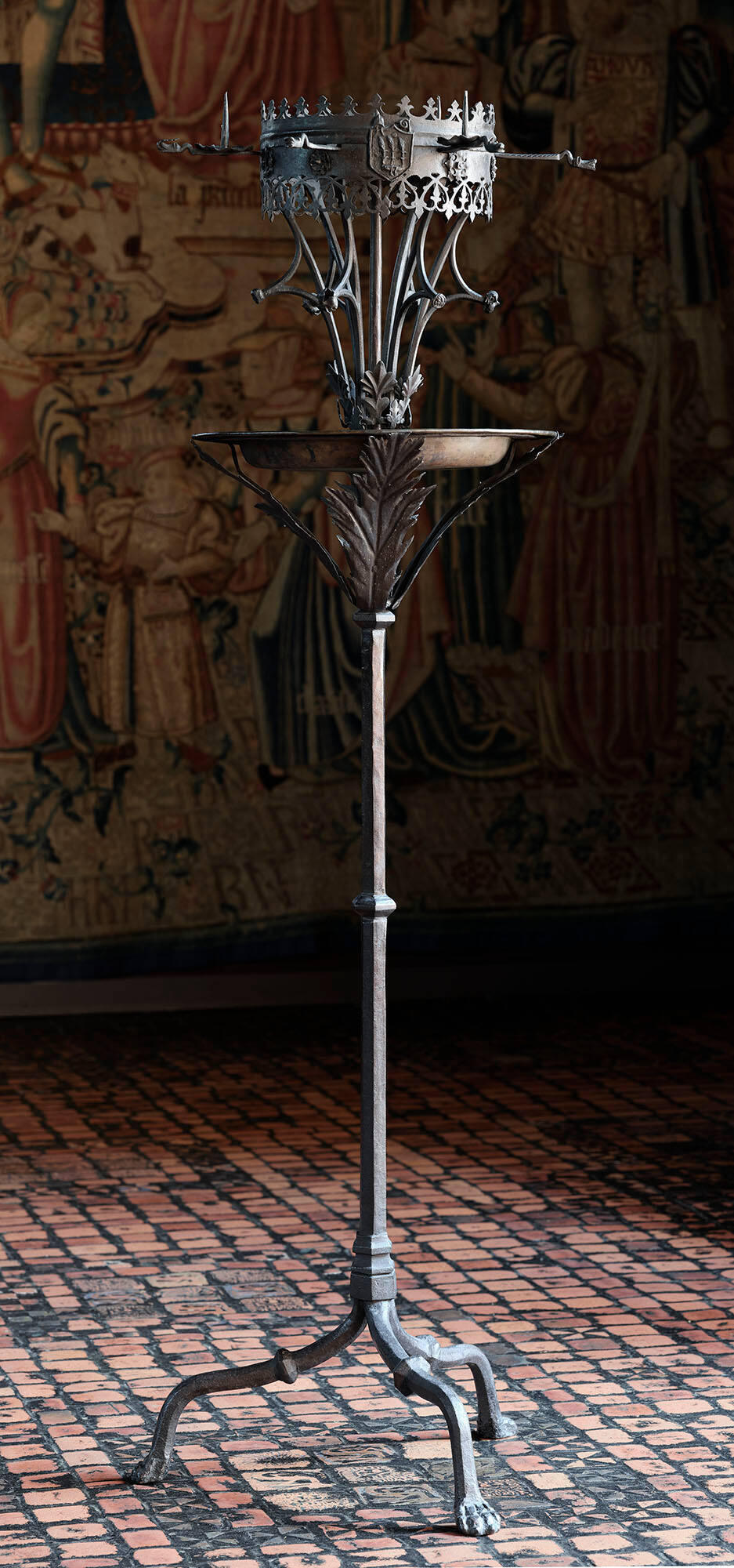 A black iron standing candelabra with a tripod claw-footed base and cylindrical top.