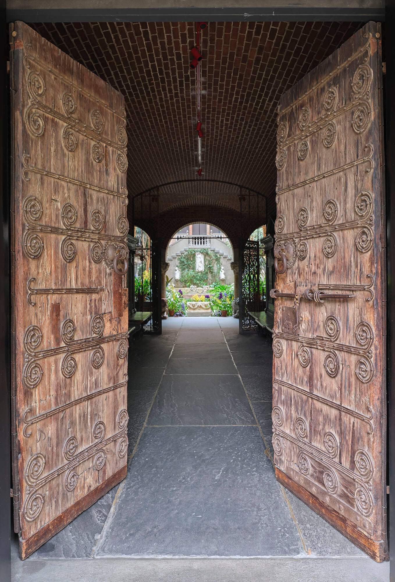 Two wooden doors with elaborate ironwork are open to show the garden courtyard of the Museum.