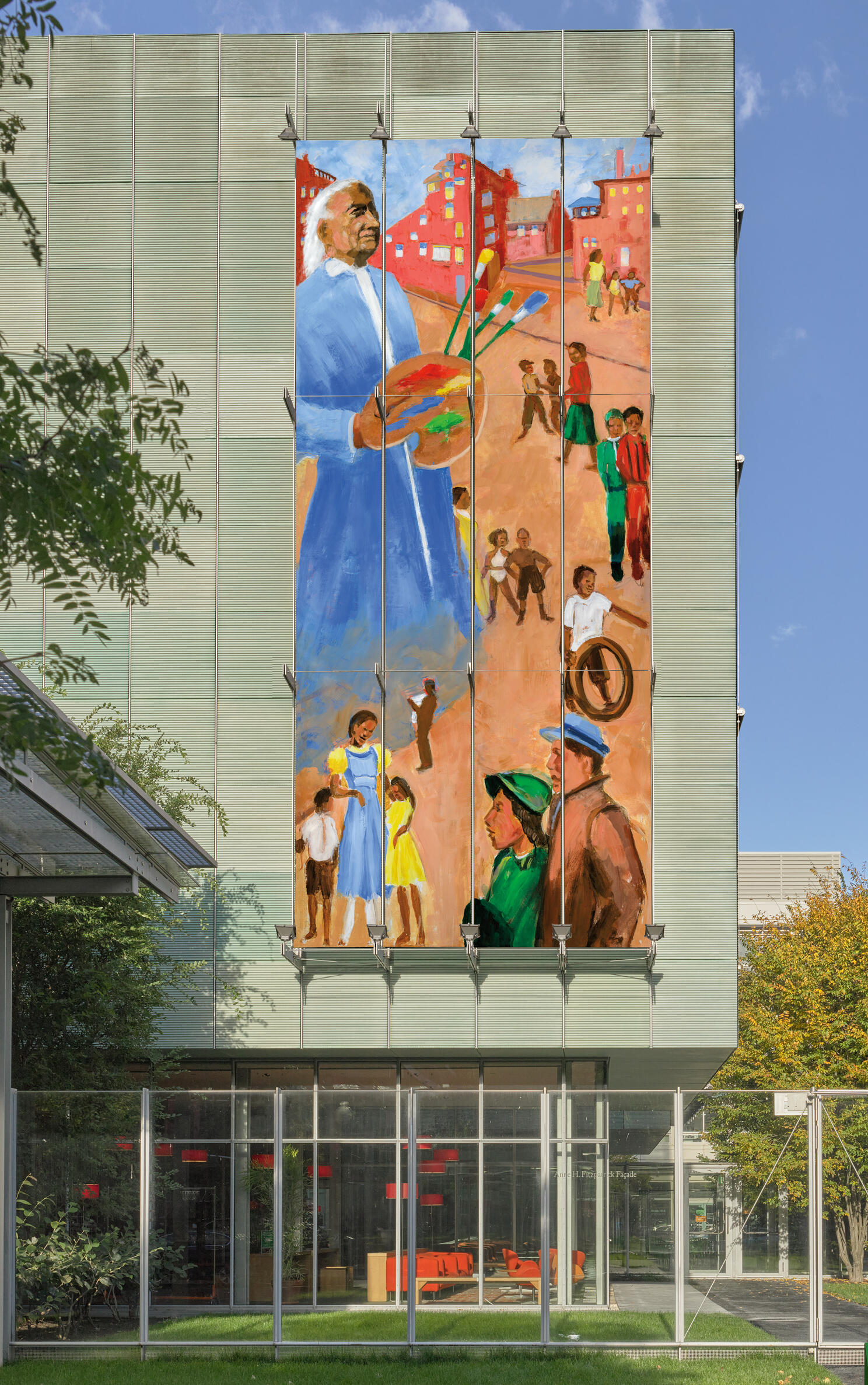 A large image on the facade of the Museum with a very tall, African American man with white hair standing among smaller groups of people, holding a paint palette. 