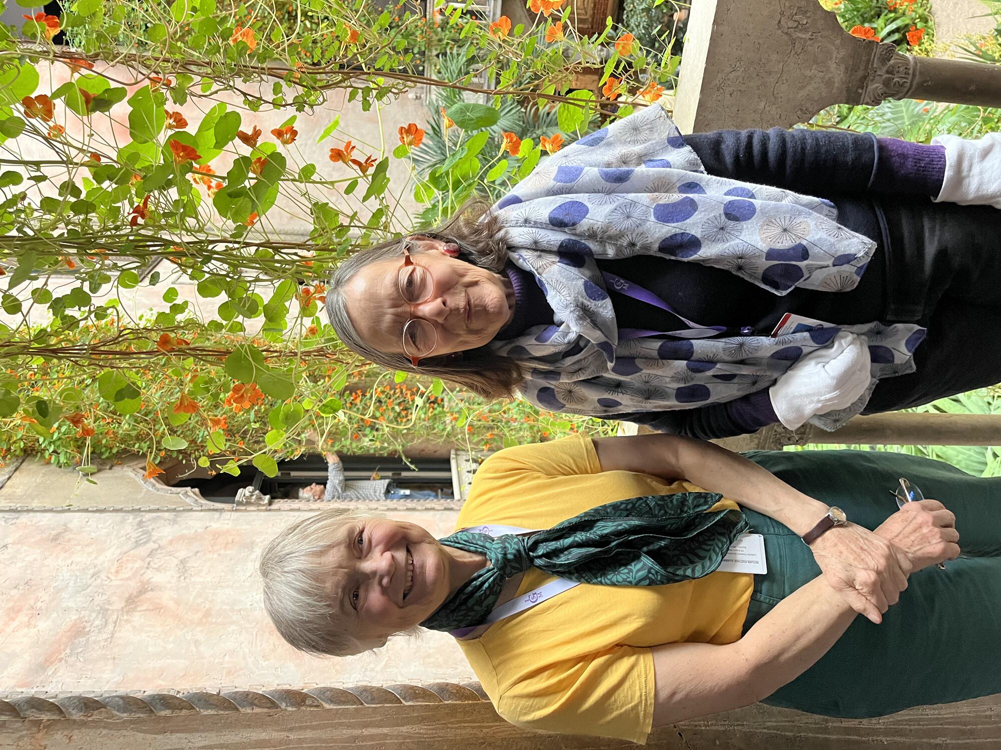 Two white women standing in a window to the Courtyard of the Isabella Stewart Gardner Museum.