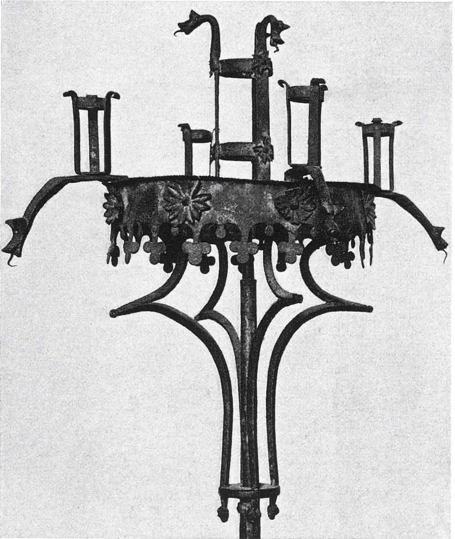  A black and white photograph of a triangular standing candelabra.