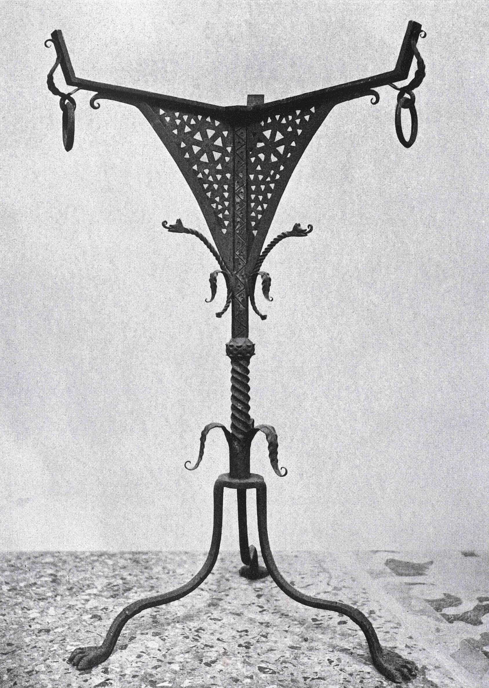 A black and white photo of an iron stand with three feet.