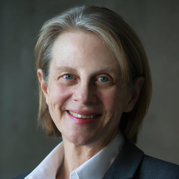 Caucasian woman with straight, chin-length blond hair wearing a white blouse and dark jacket smiling at the camera