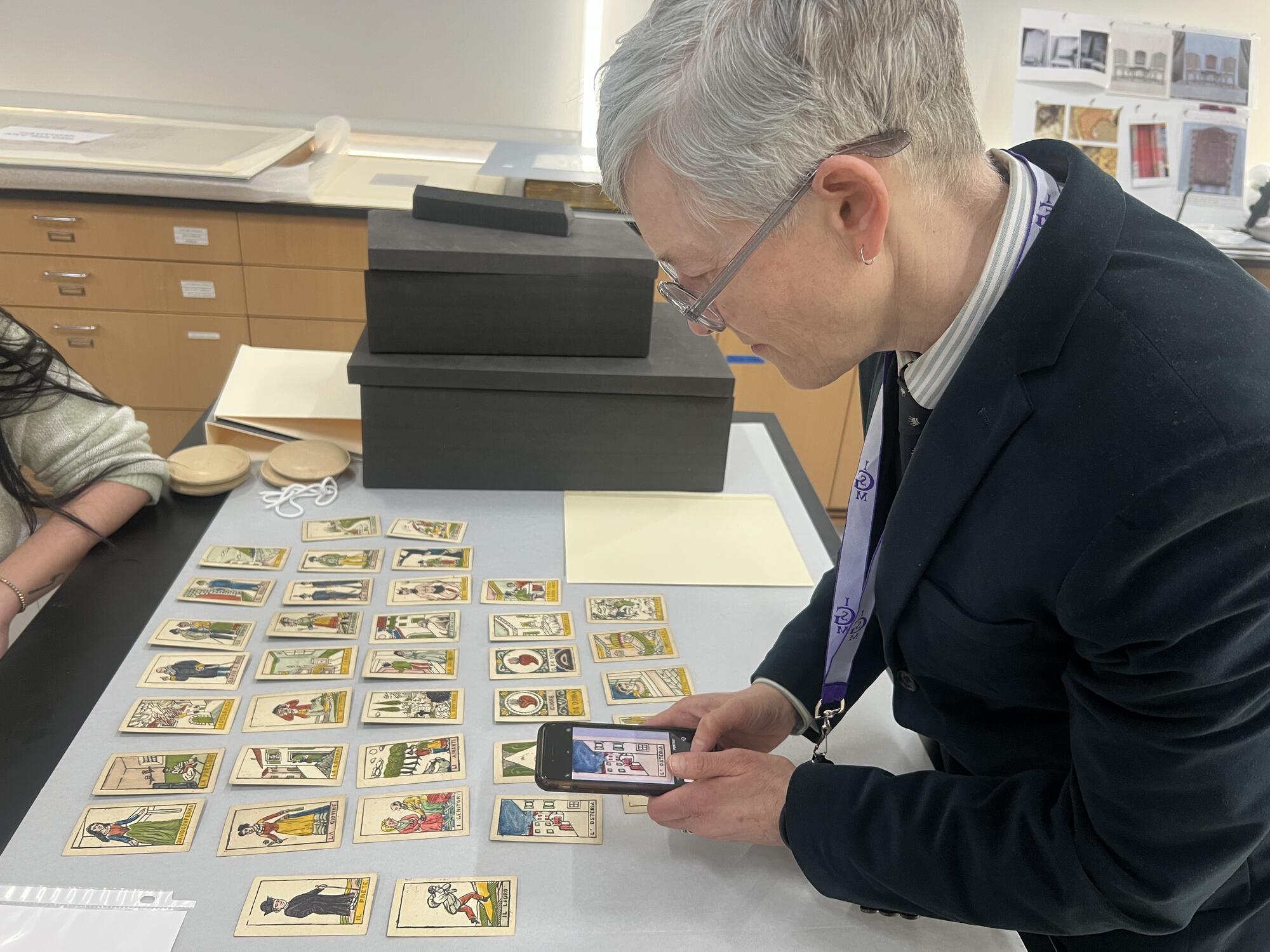 Side view of a  person with short grey hair looking down on cards lined up on a table.  