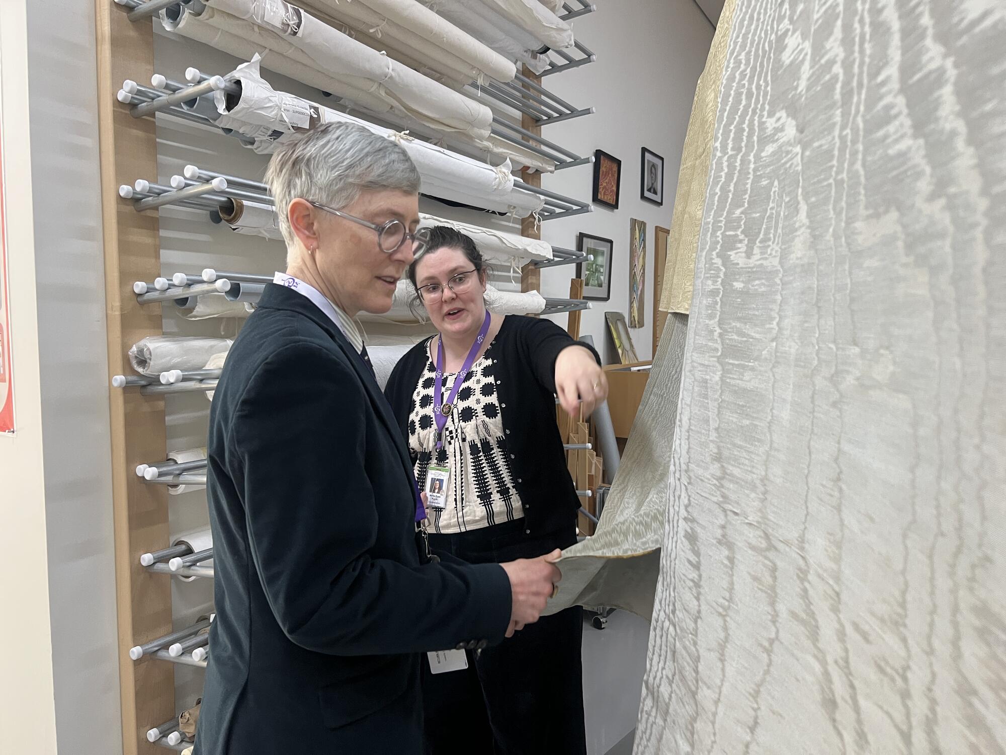 Woman with short grey hair and suit jacket examing a piece of fabric