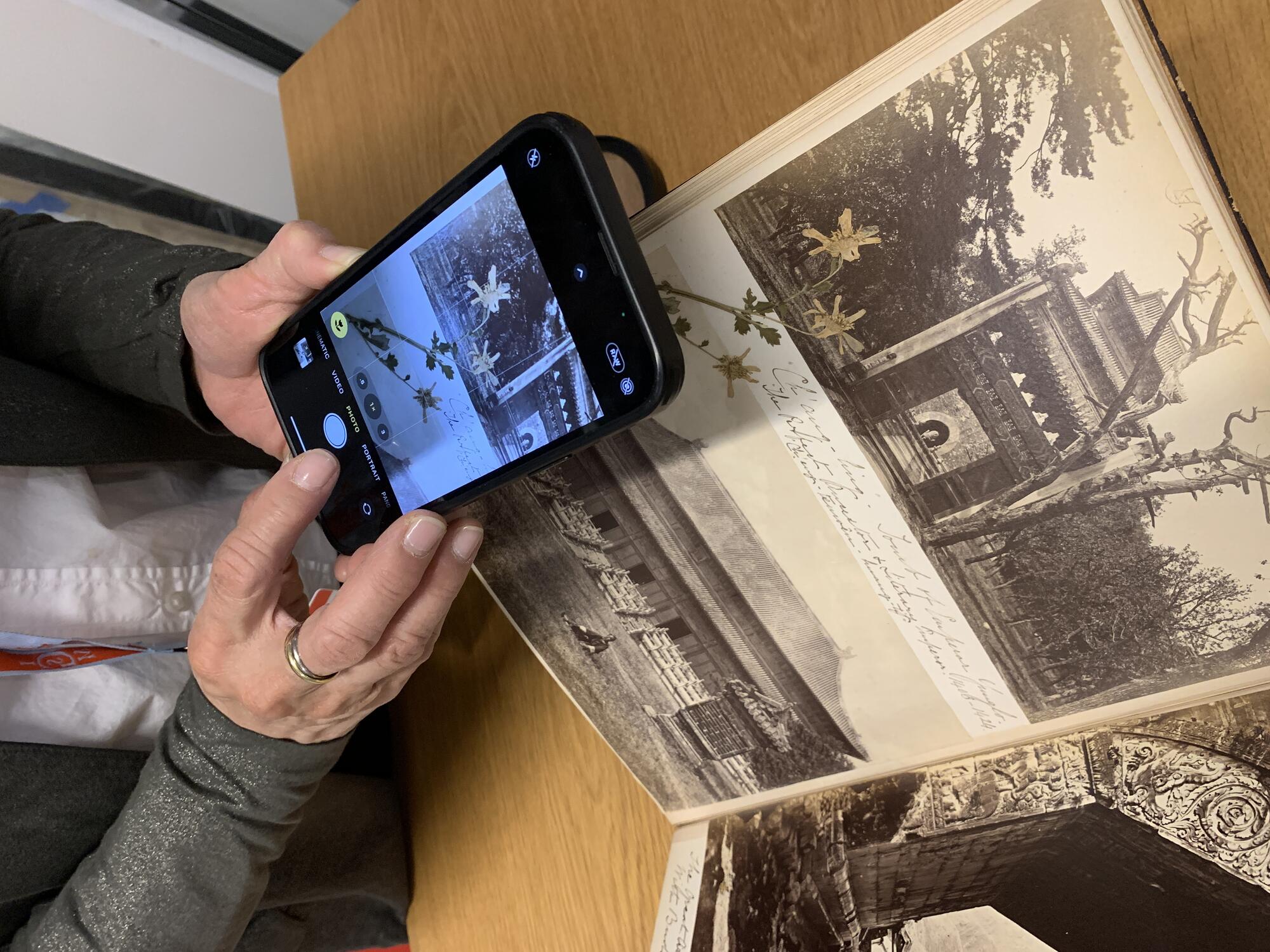 A person photographing a page of a scrapebook with a smart phone. 