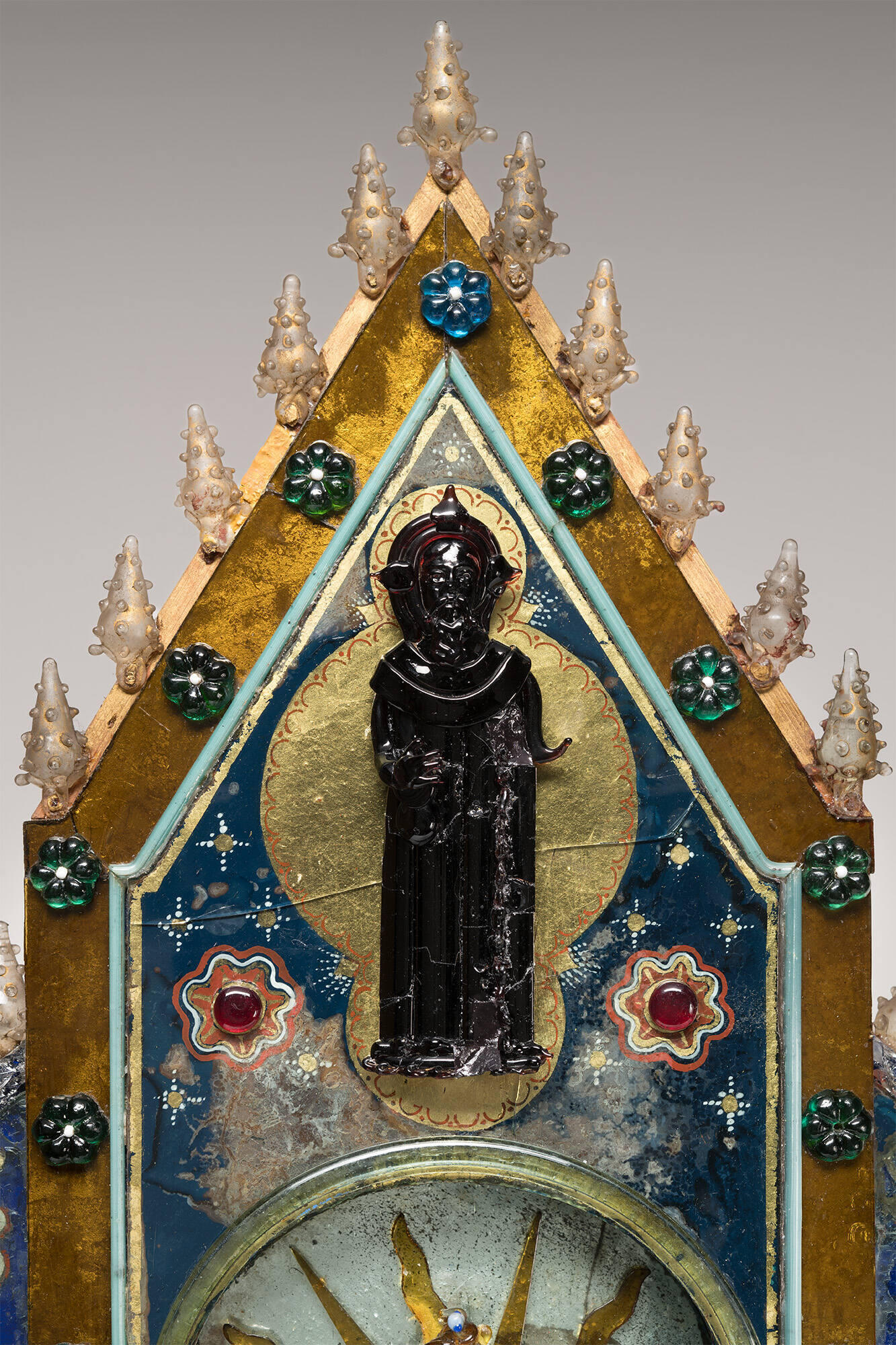 A black glass figure representing God the Father near the top of the vitrine