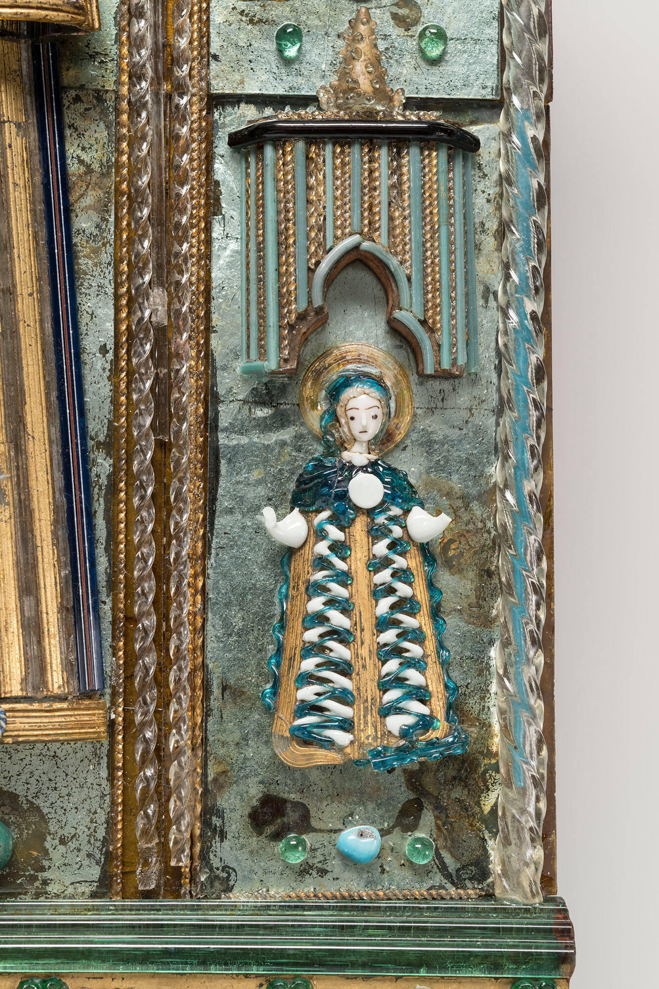 A female saint with a white face and a halo made out of glass.