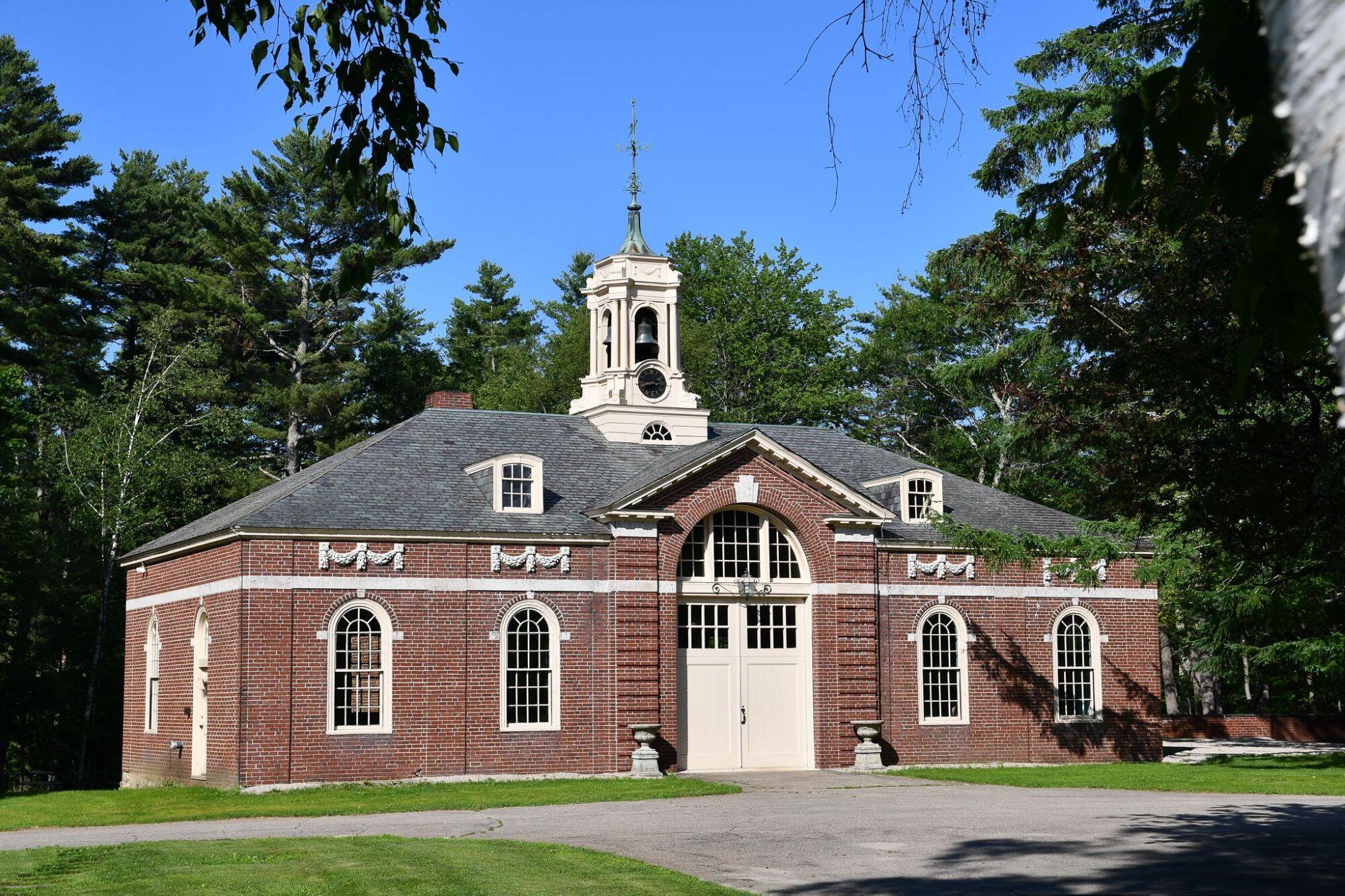 Red brick building with several windows and large white arched garage doors.