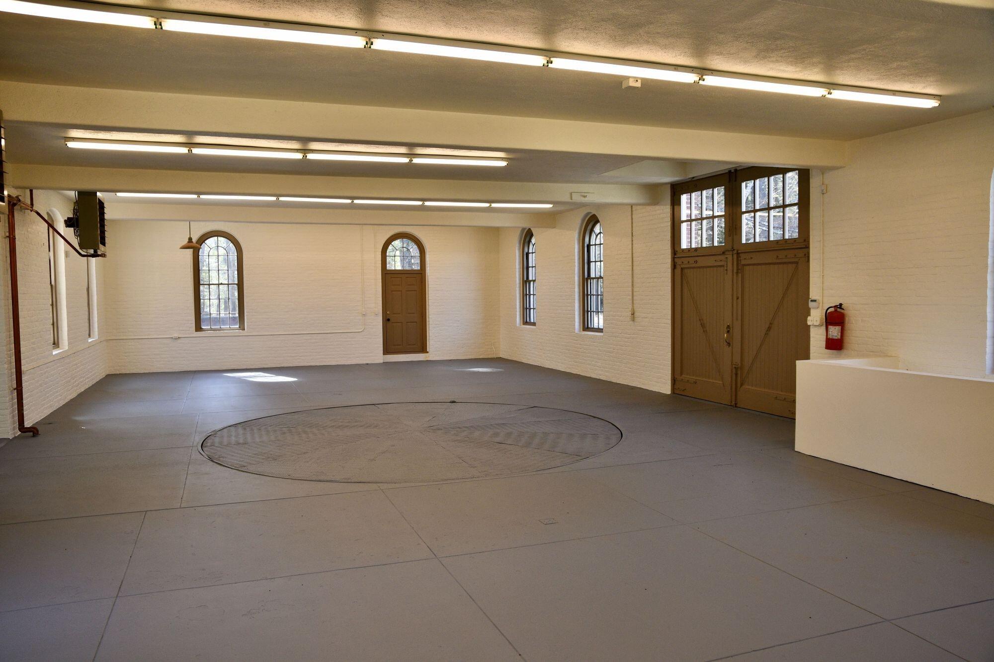 Interior of brick building painted white, with several arched windows and doorways.