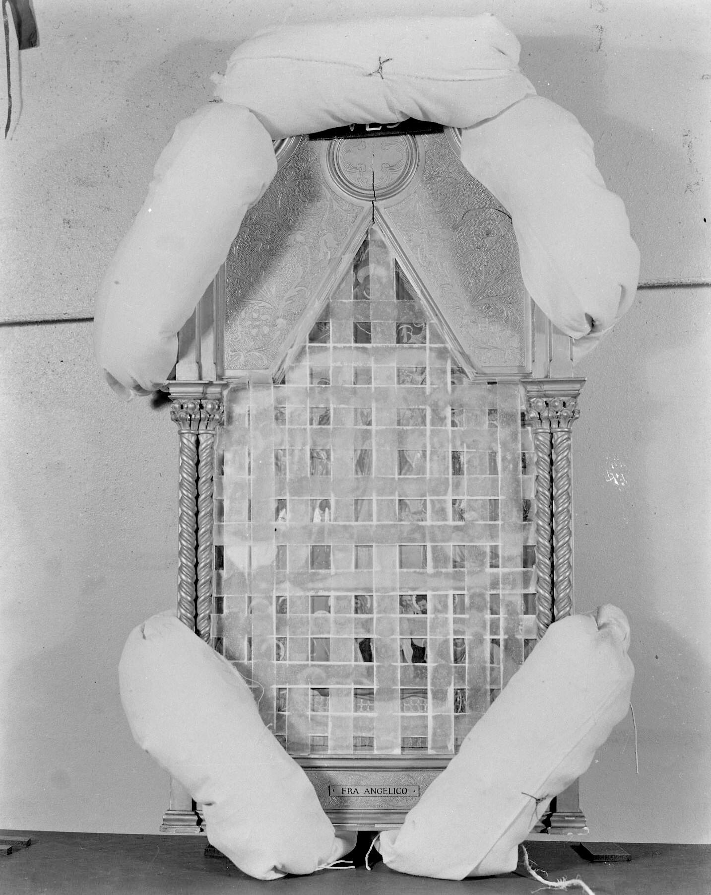 Ornately framed painting surrounded by packing pillows and criss-cross strapping across the painting's surface.