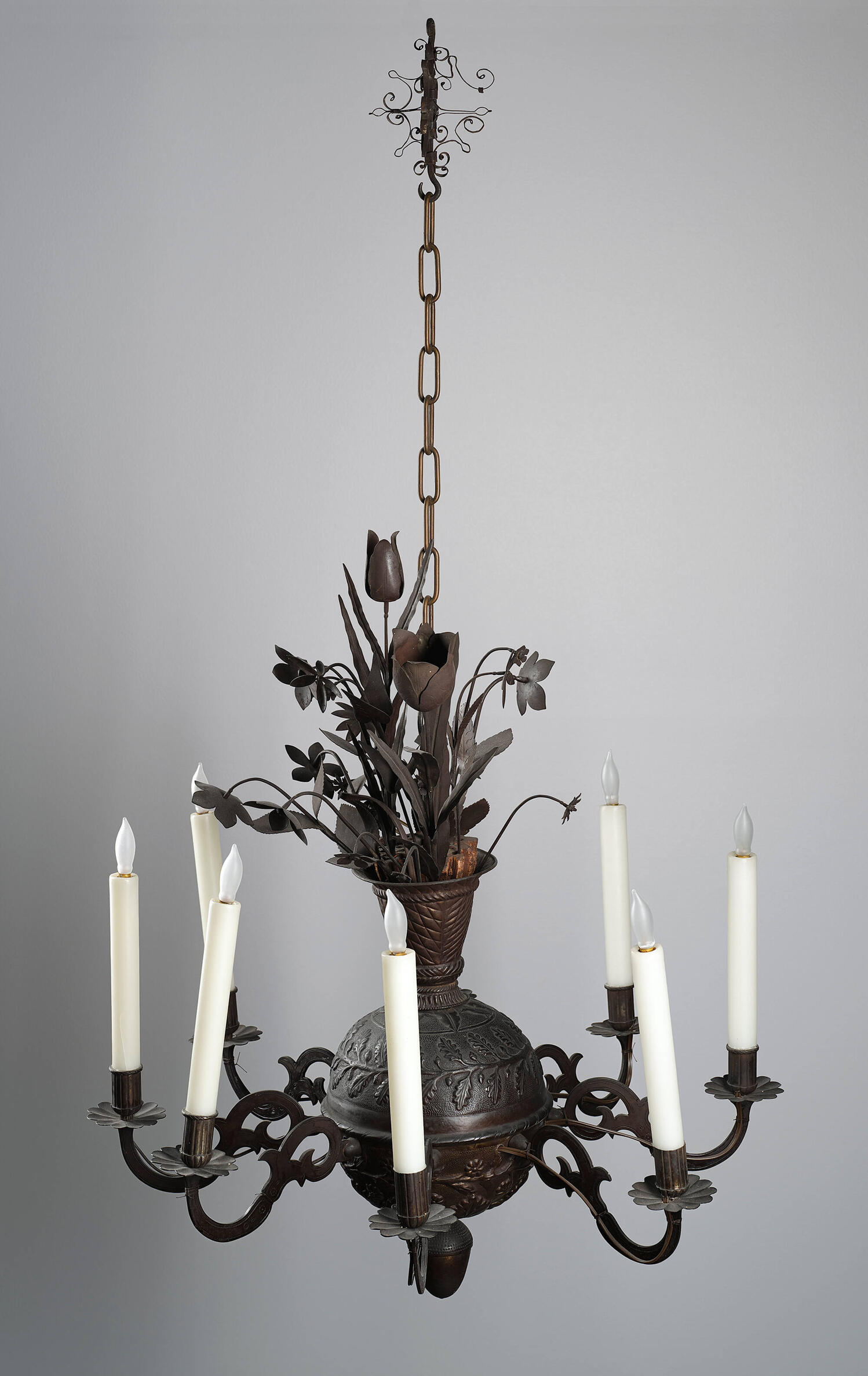 Iron chandelier with 6 faux candles. At the center is a vase with flowers.
