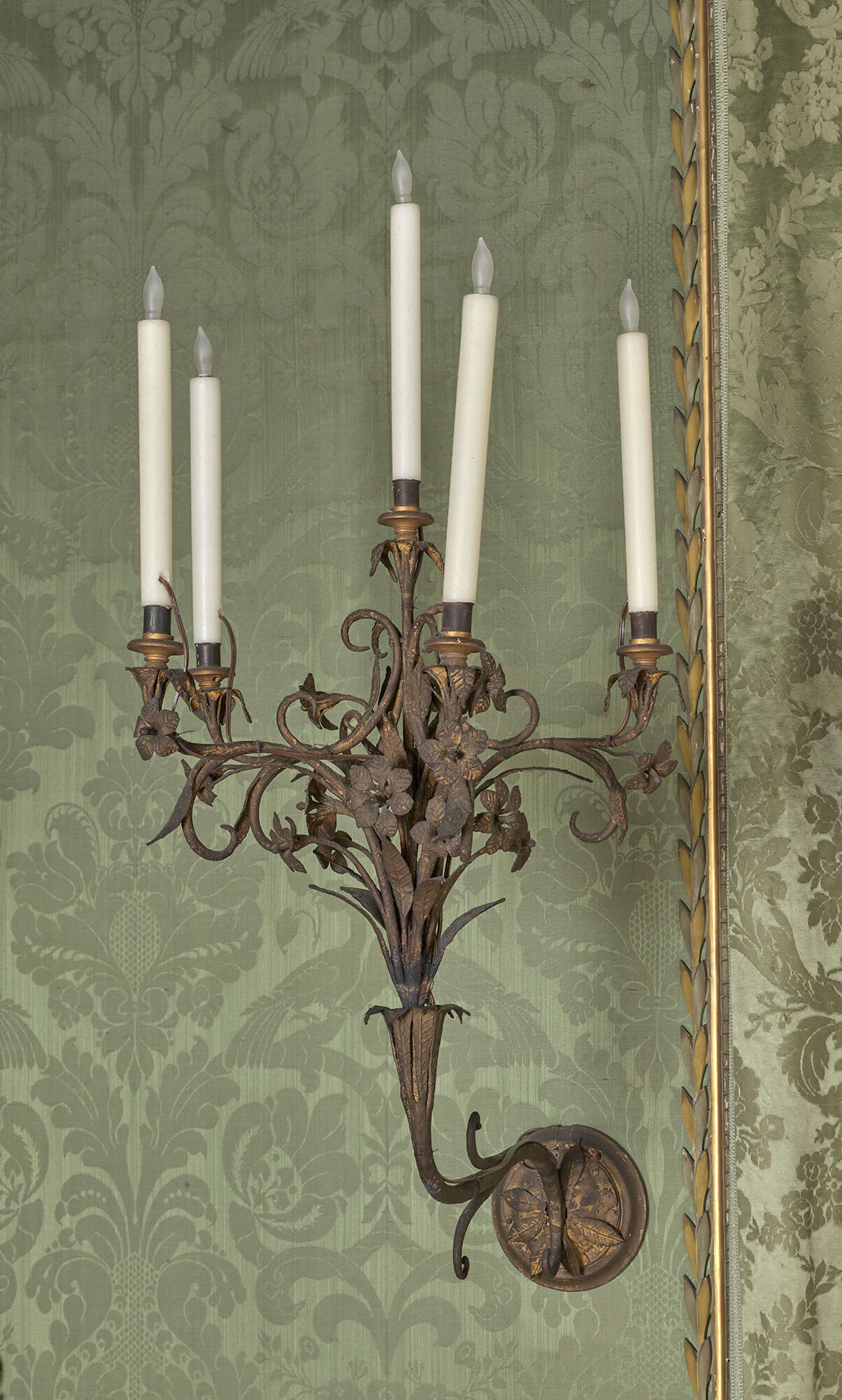 Iron wall sconce for five candles with decorative scrolling leaves and flowers.