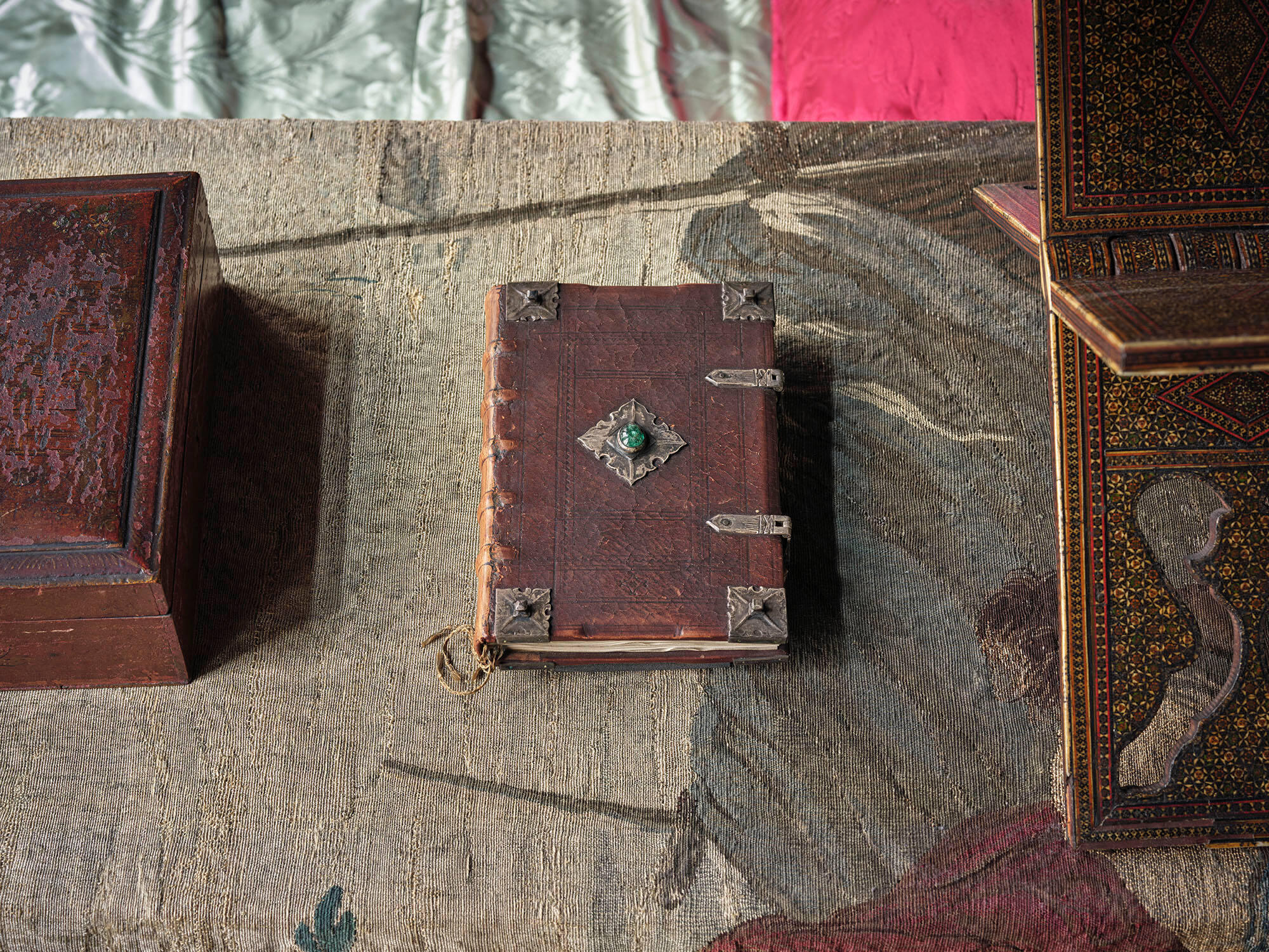 A brown leather bound  book with silver fittings and a green emerald.
