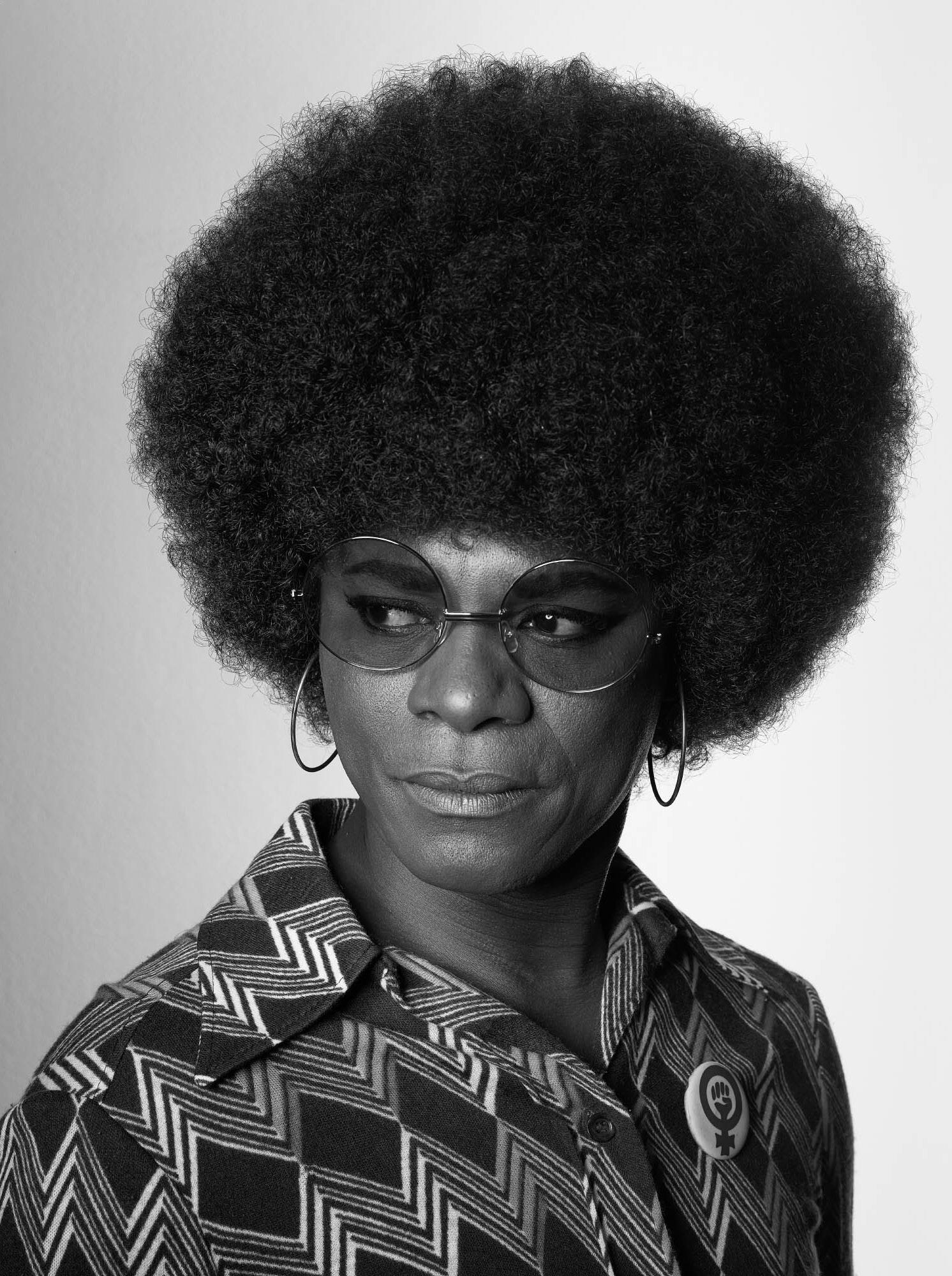 Black and white photograph of an African American woman with a large afro and glasses looking towards the side. 