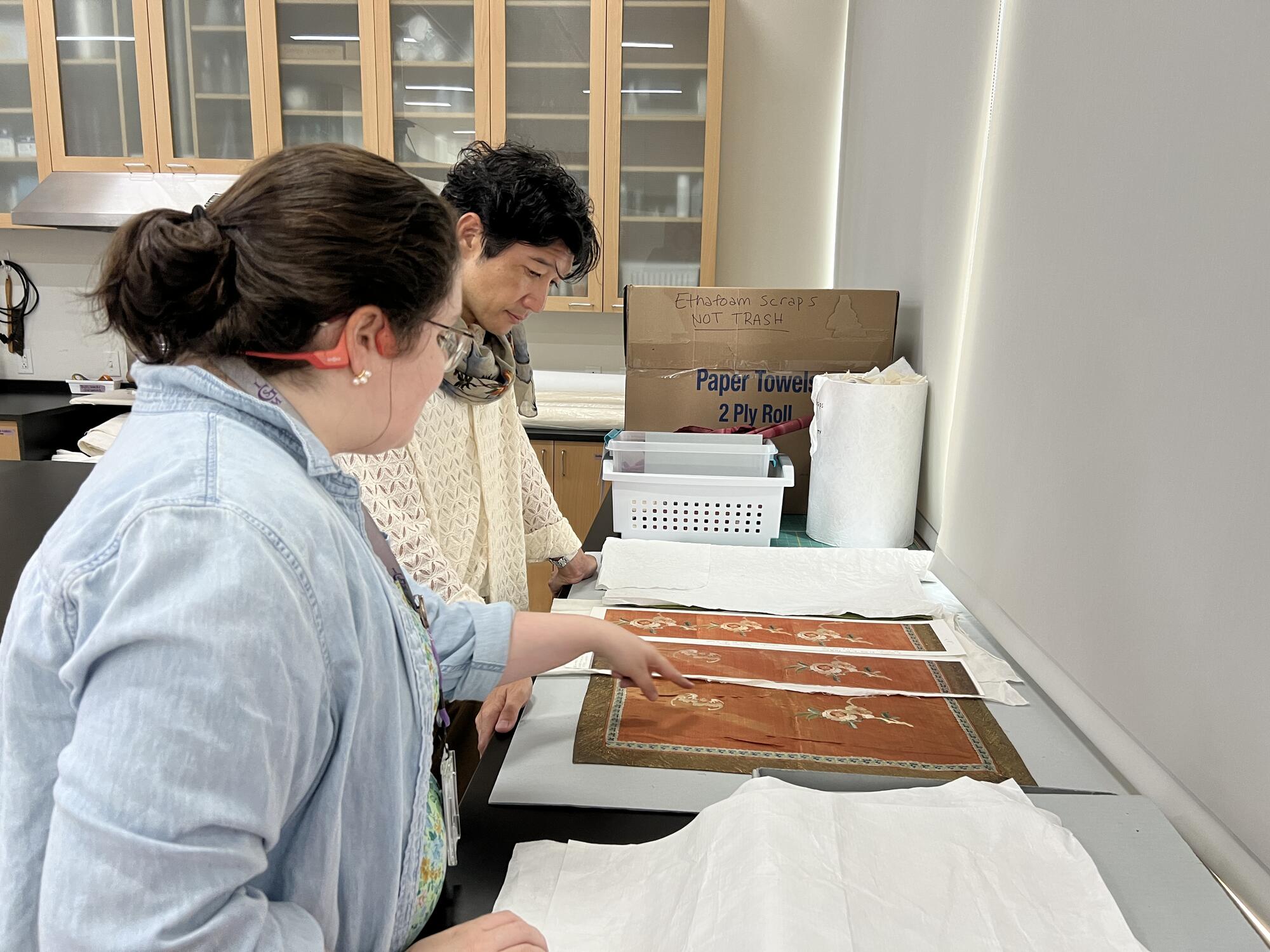 A caucasian woman showing a Chinese textile with an Asian man. 