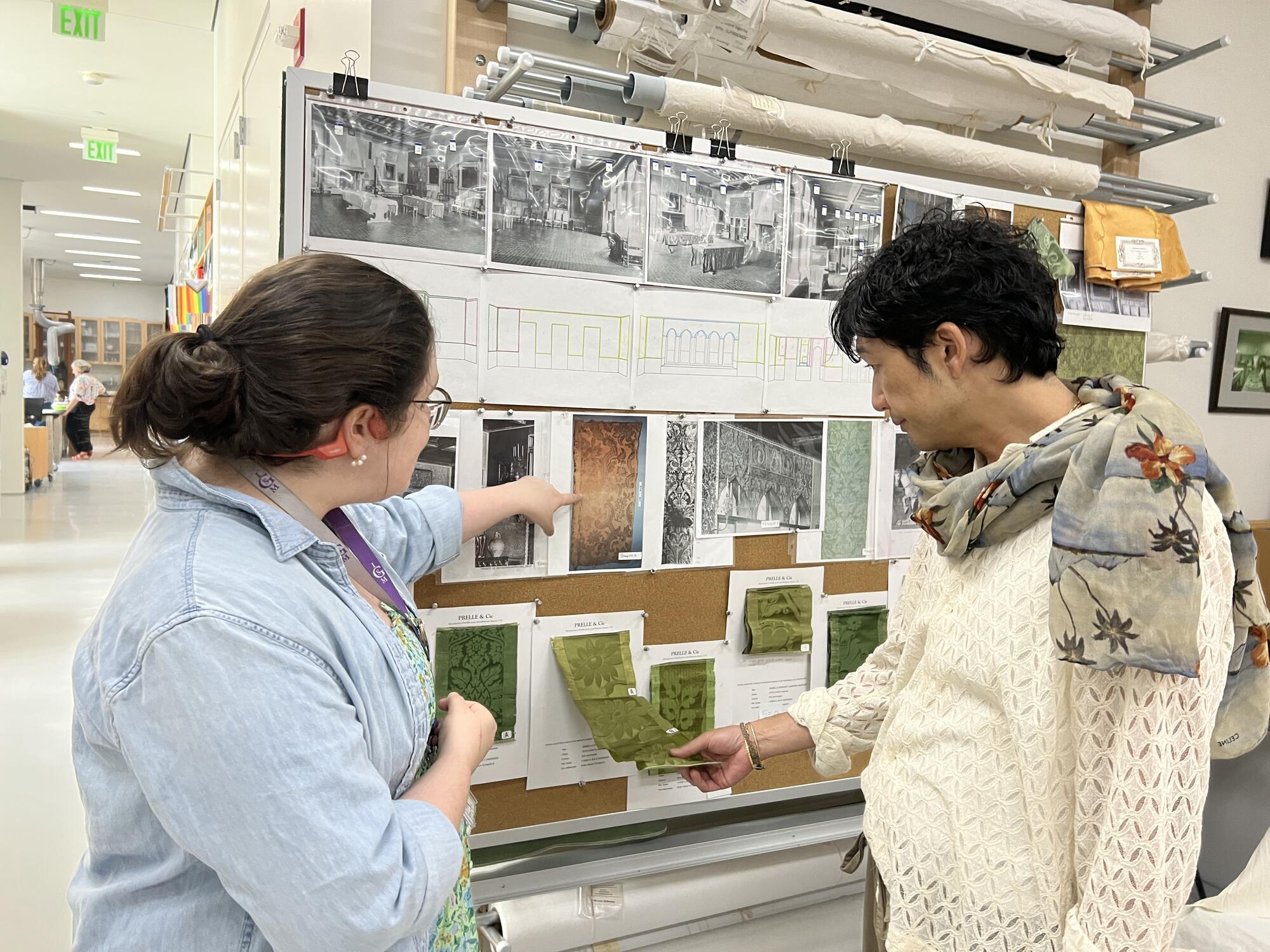 A woman pointing out textile samples to an Asian man.