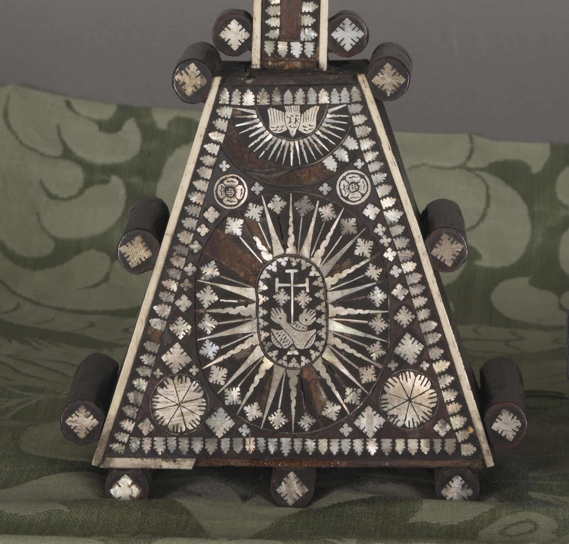 Detail photo of the cross showing areas of bone and mother-of-pearl loss on the cross.