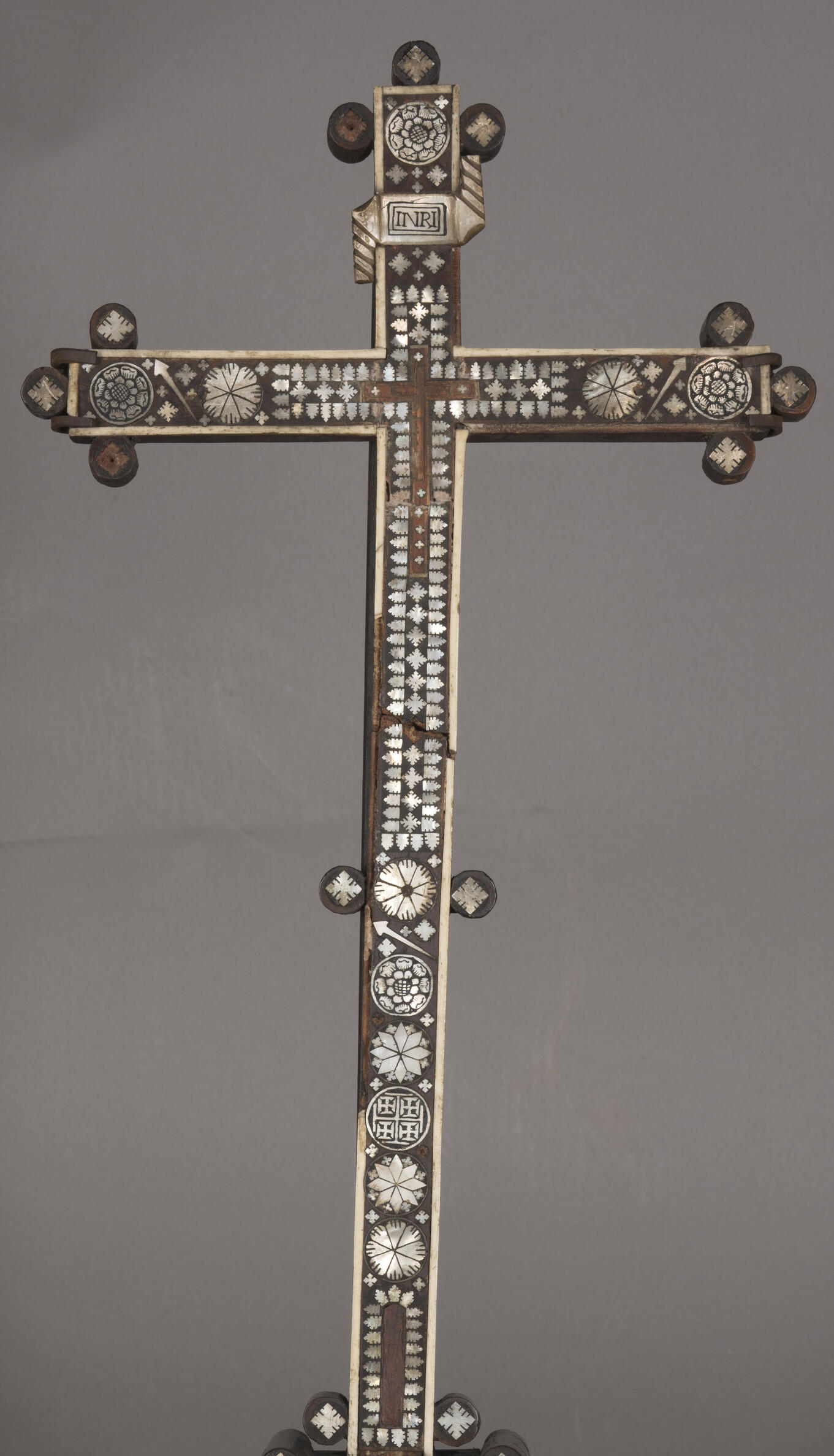 Detail photo of the cross showing areas of bone and mother-of-pearl loss on the cross.
