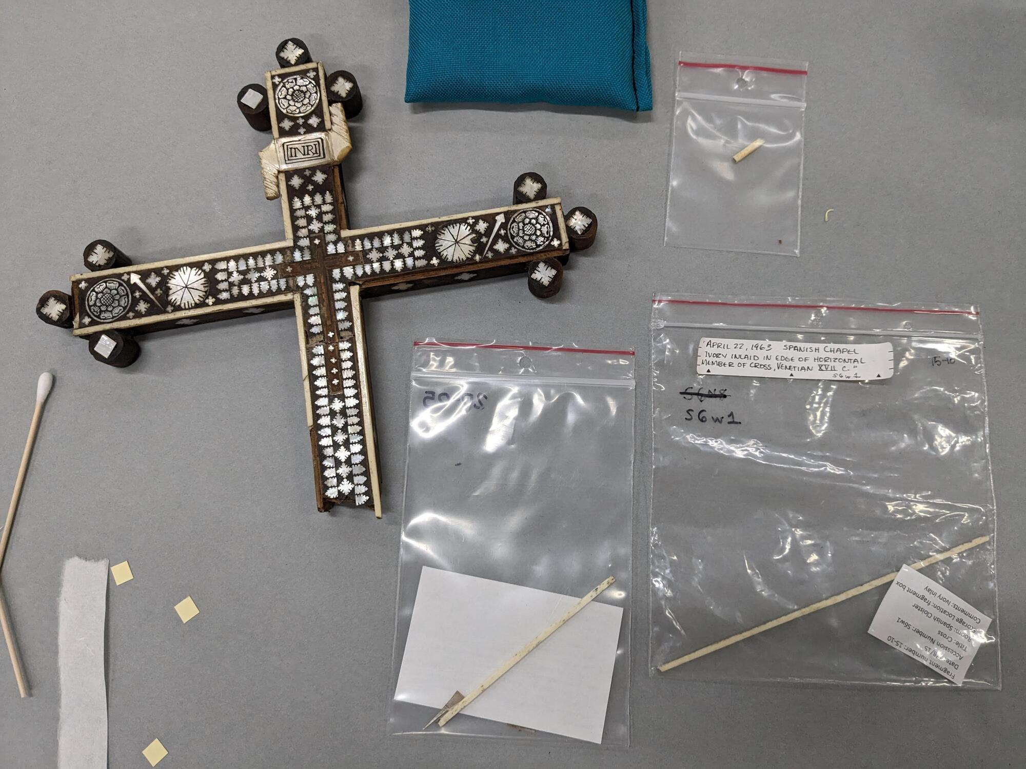 Top of the cross next to three bone fragments in plastic bags found in storage.