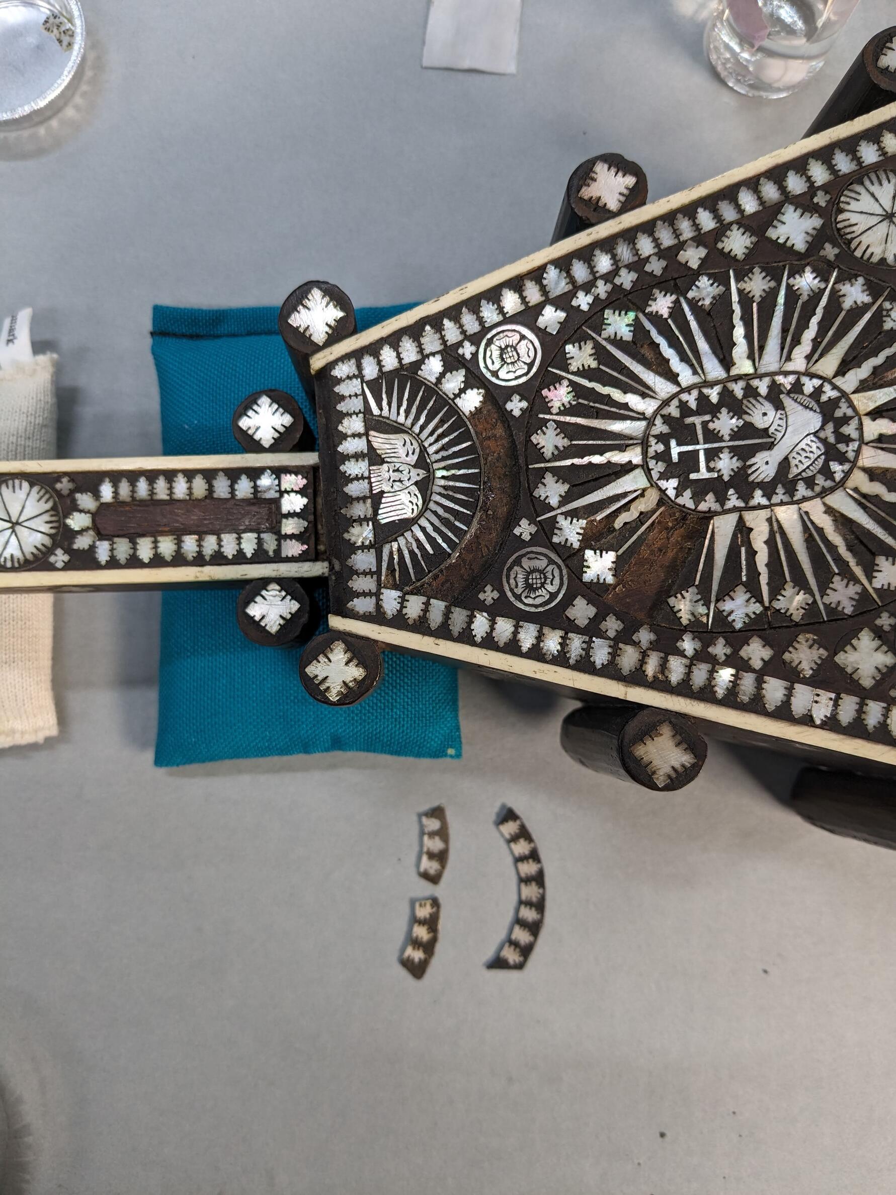 Mock up mother-of-pearl replacement pieces laying next to the base, near the area they will be attached to.