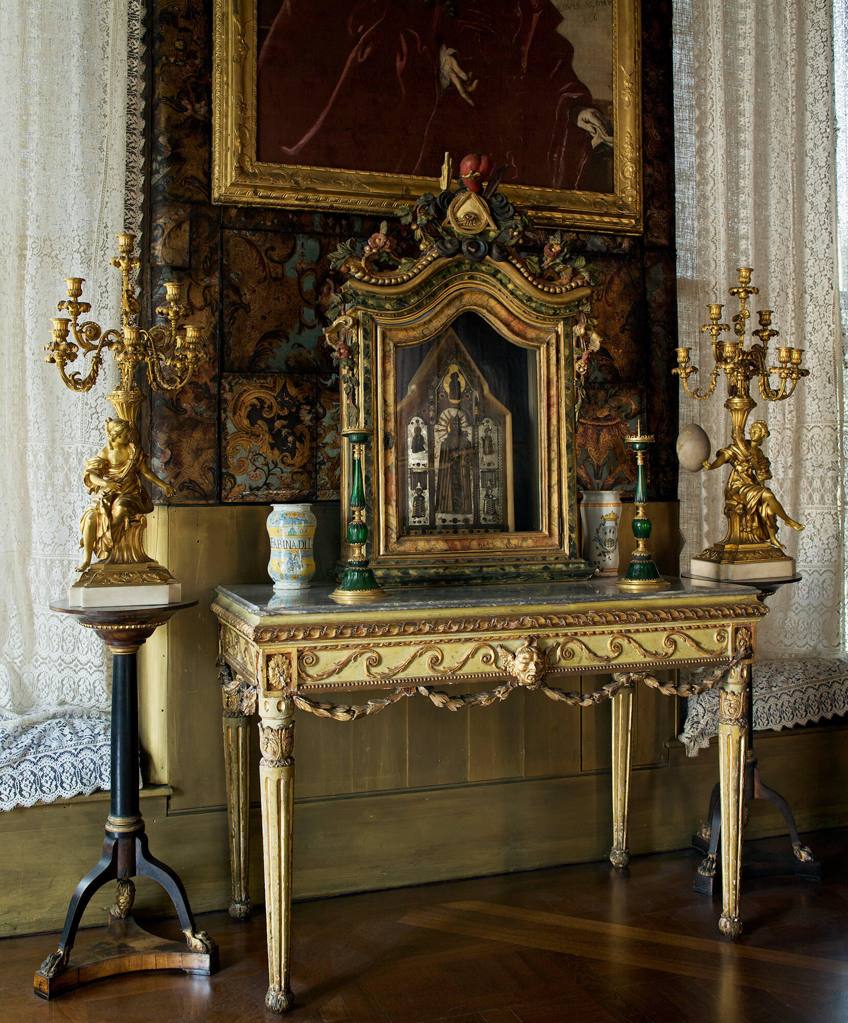 The Black Glass Madonna displayed in the Veronese Room gallery.  The sculpture sits on a painted and gilded table inside a painted and gilded wooden vitrine. 