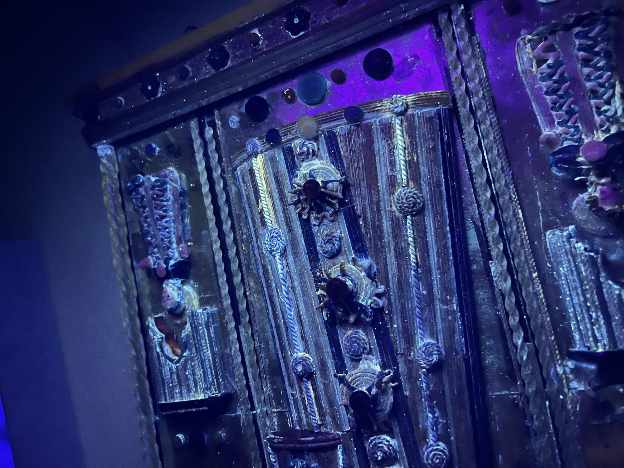 Detail of sculpture observed under ultraviolet light which appears purple with areas of adhesive residues fluorescing a bright whitish-blue color as well as a bright pale yellow color.