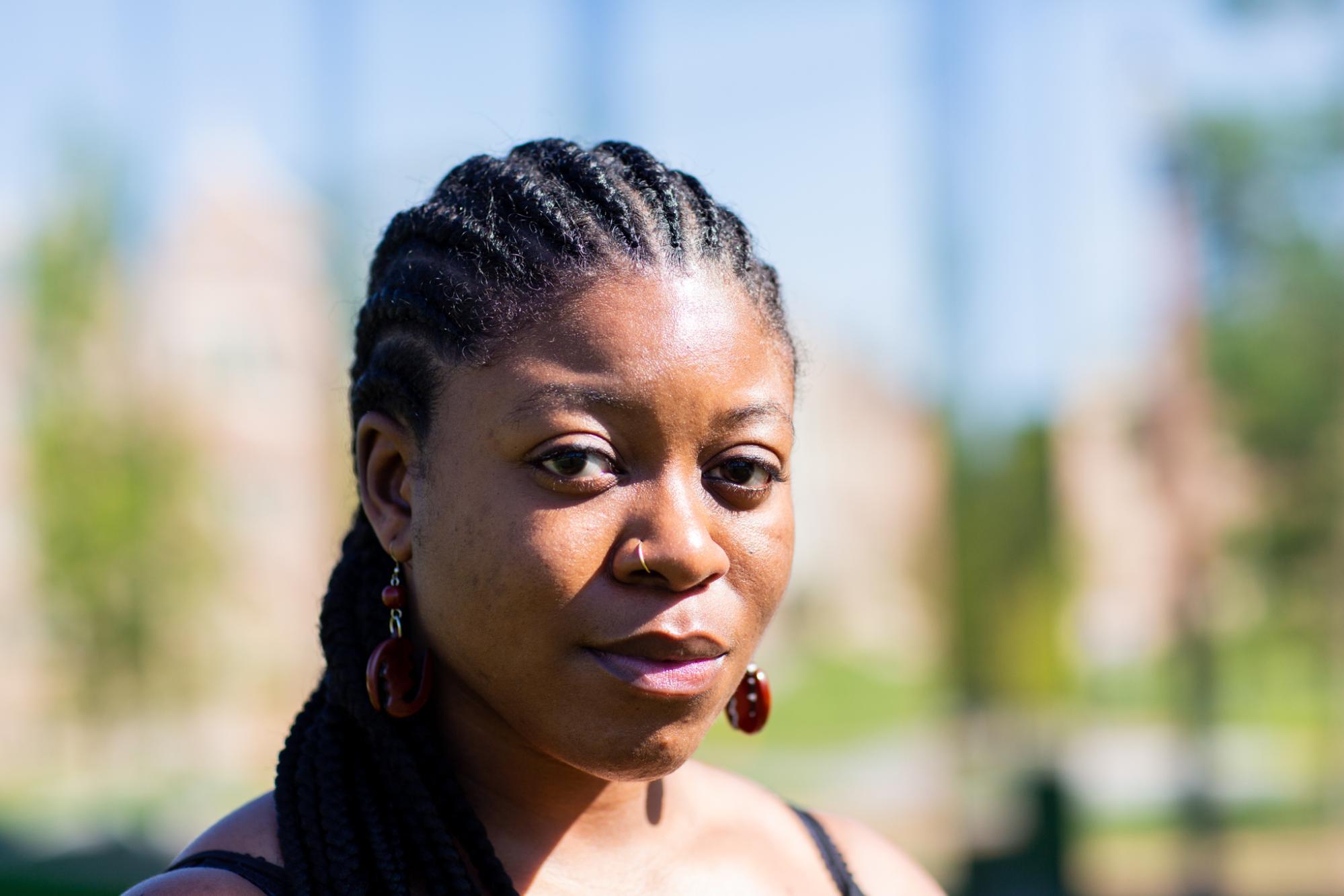 African American woman with long corn rows and braids looking confidently at the camera. 