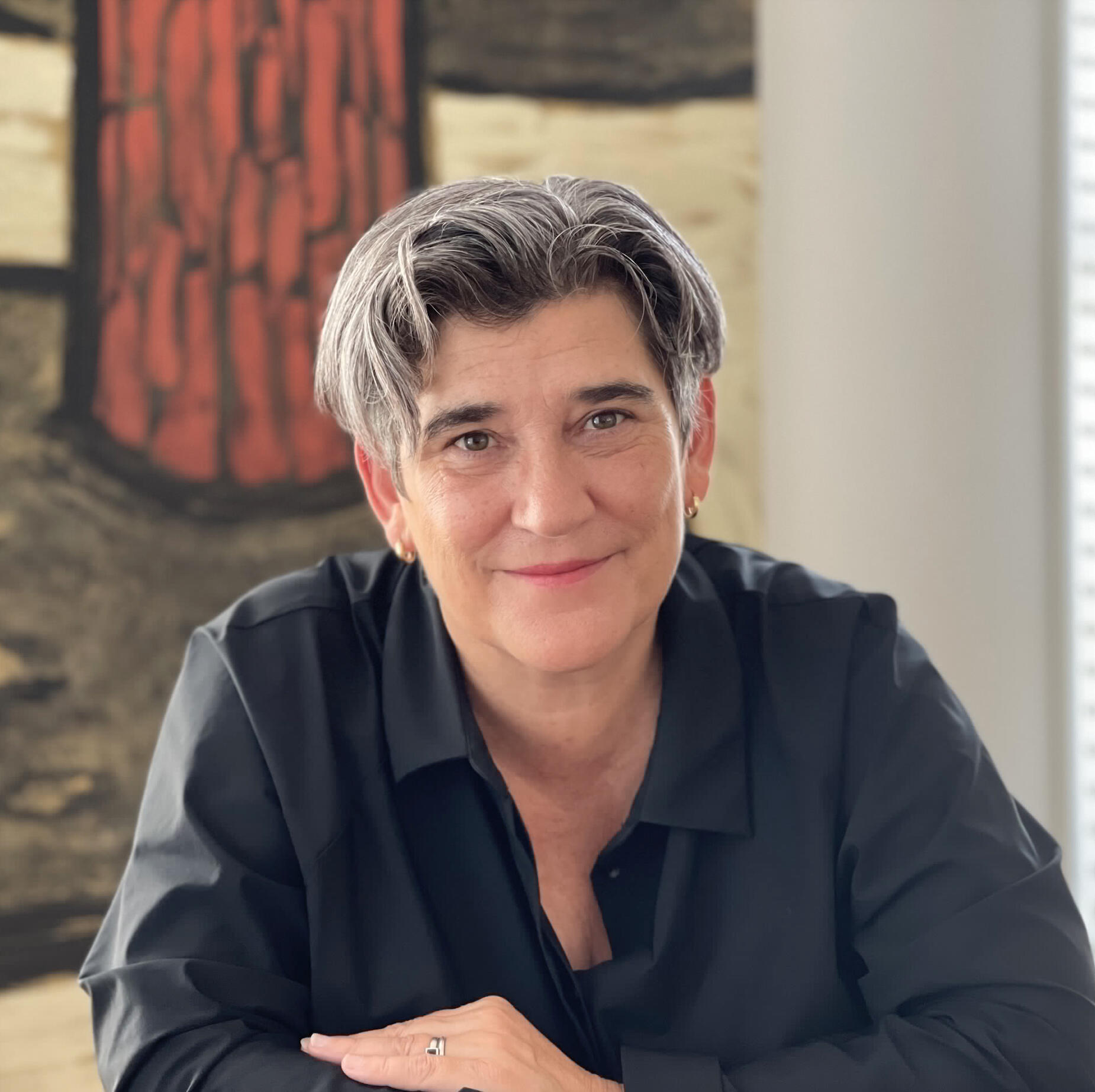 Headshot of a woman with short, greying hair, looking directly at the camera. 