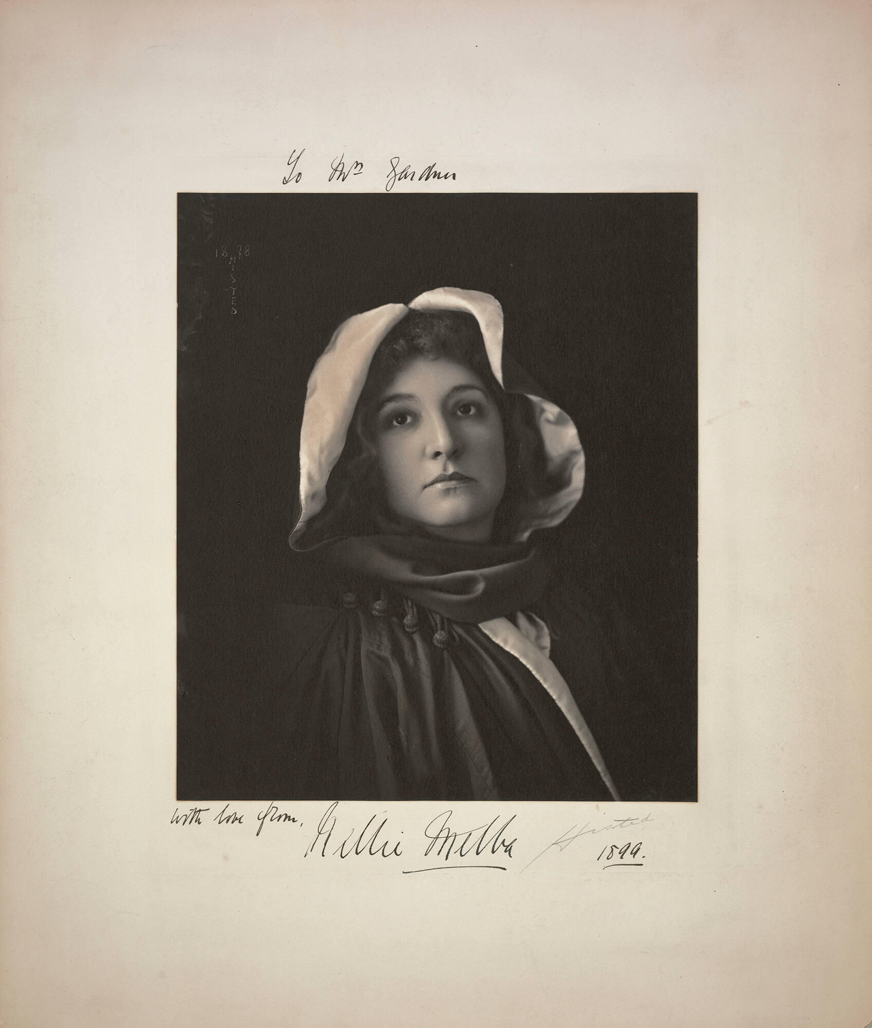A black and white photograph of Nellie Melba, a white woman with dark hair, wearing a hood and cape.