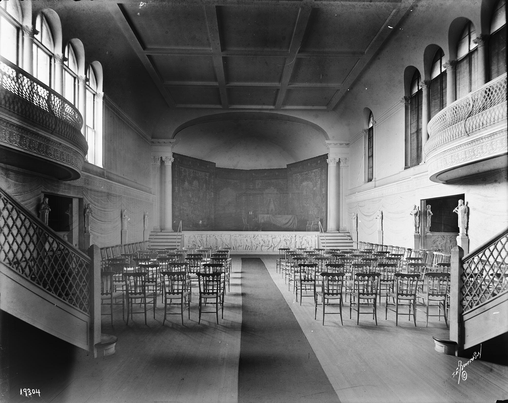 A black and white photograph of a concert hall with a stage and seats.