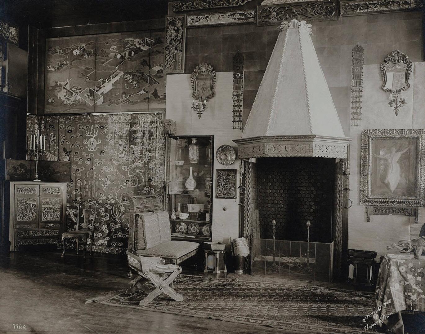 A black and white photograph of a room with Asian art work, a portrait of Isabella Stewart Gardner, and a fireplace.