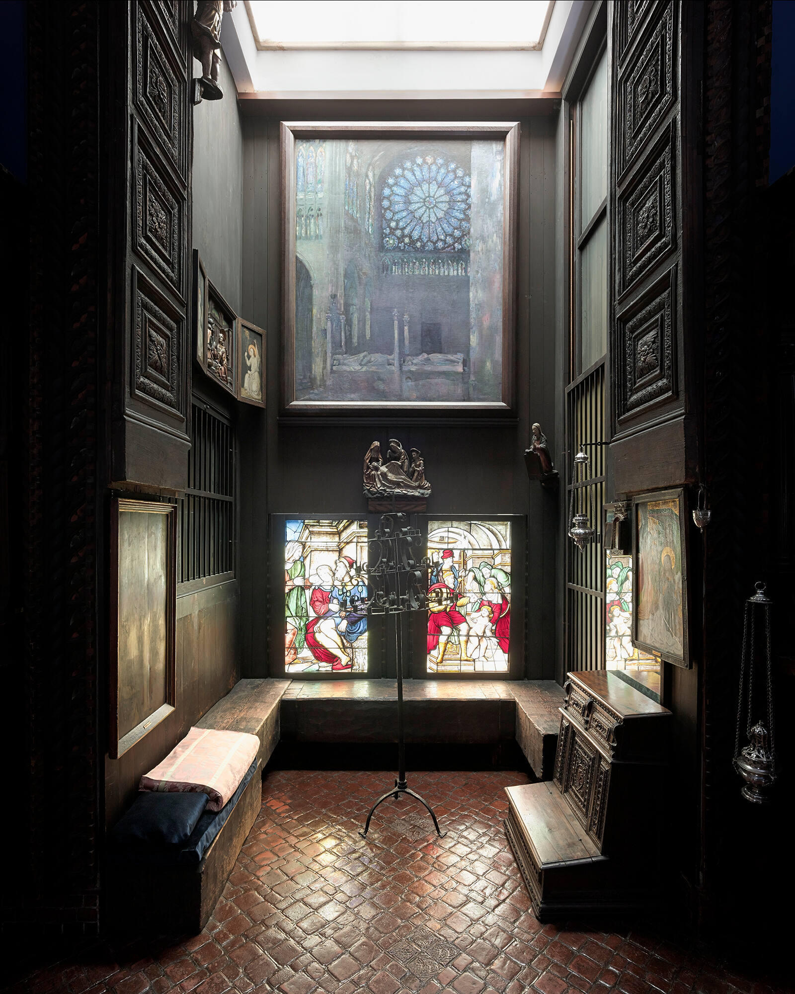 A niche with a painting of the interior of a cathedral with a large rose window over two smaller stained glass windows.