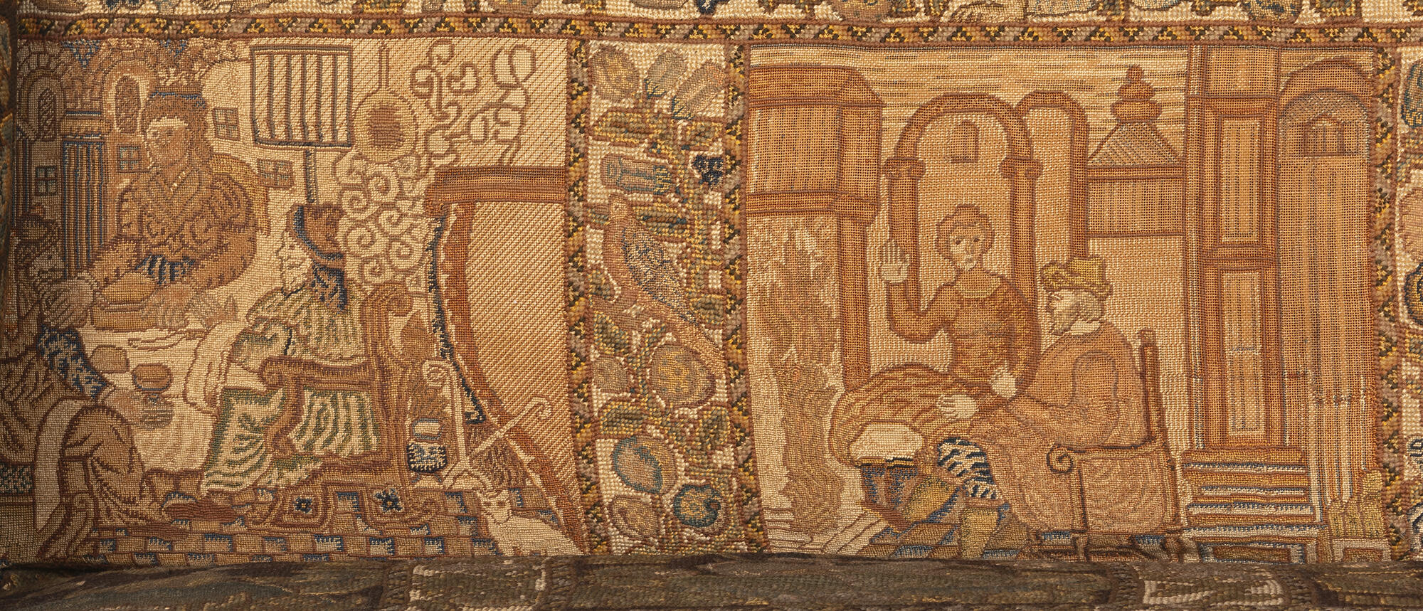 Two embroidered squares. The left with an indoor feast. The right with a couple around a hearth with a fire.