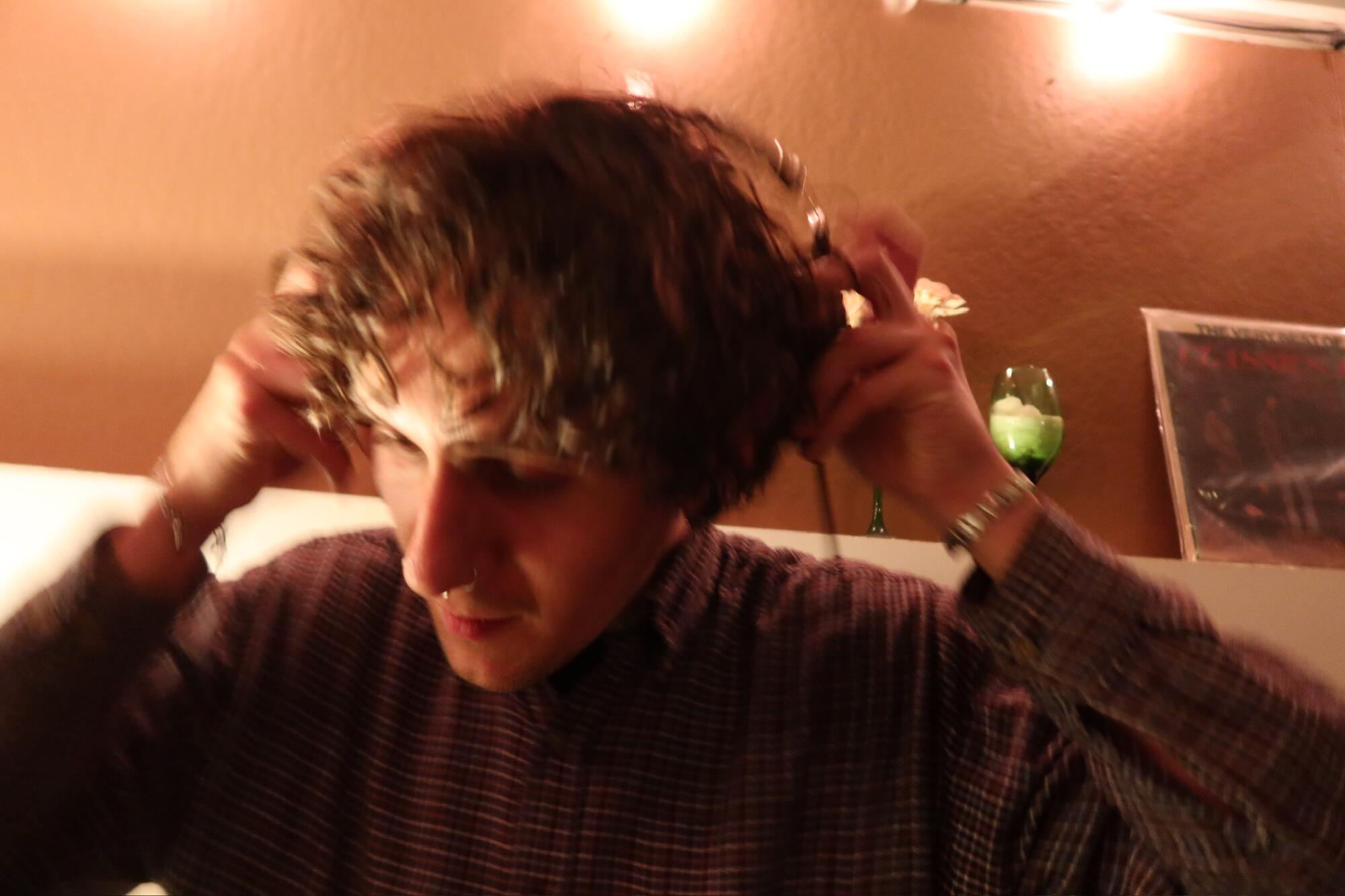 A white man with curly hair placing headphones over his ears